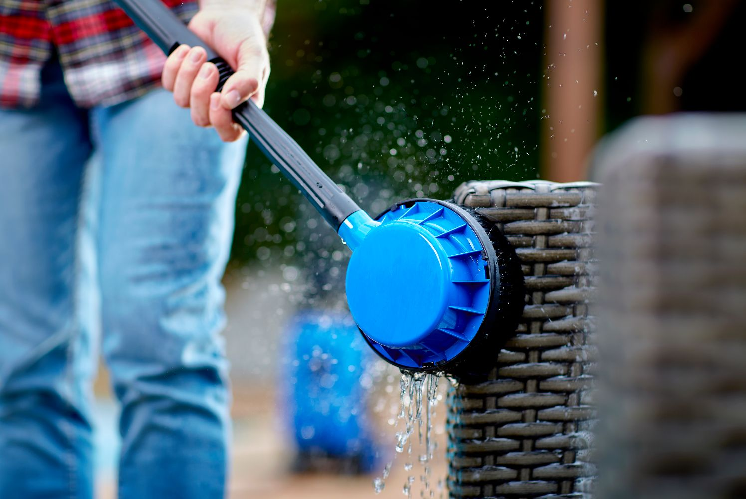 A person cleans a wicker furniture with a blue brush.
