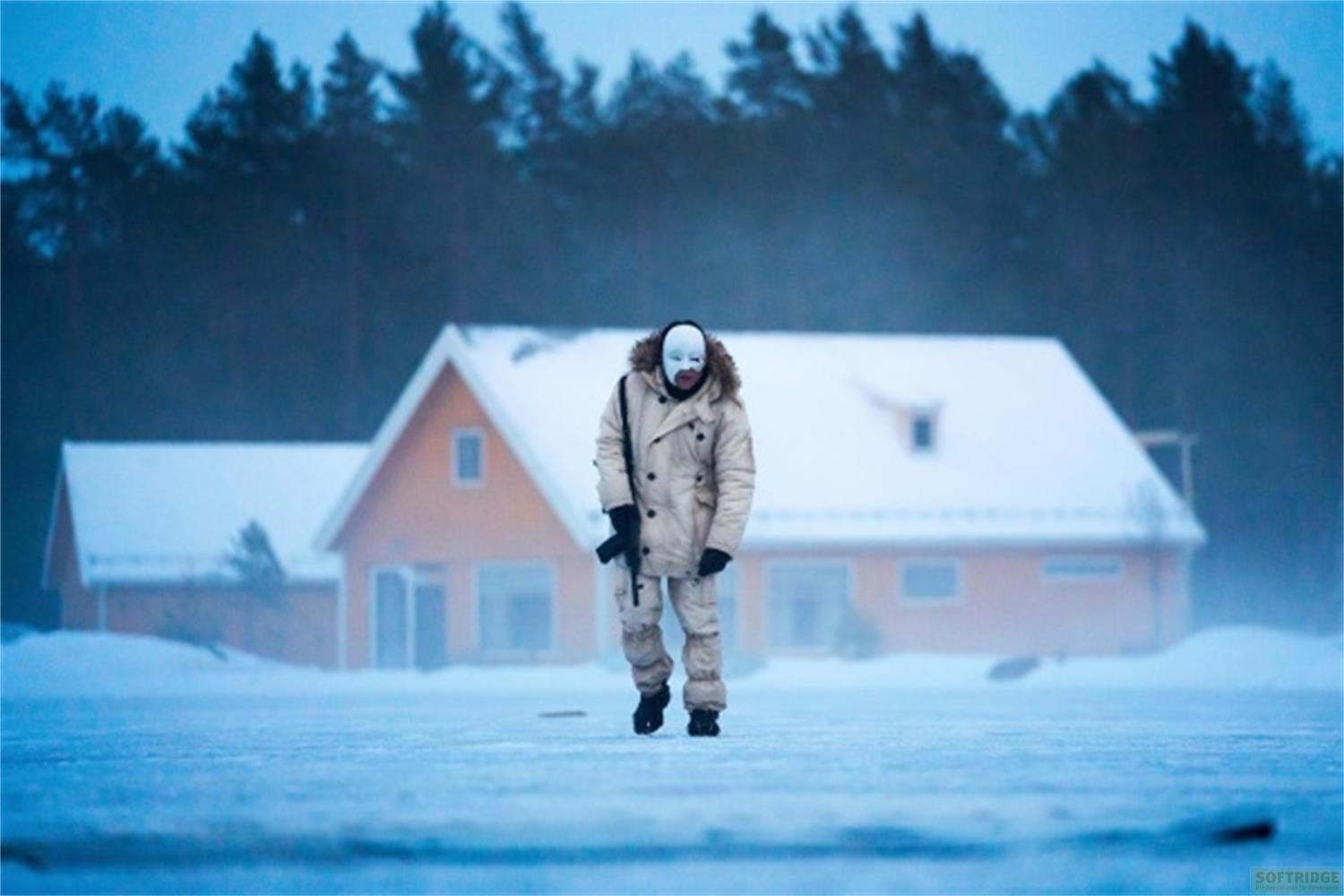 Uomo con maschera bianca e vestiti invernali con fucile in paesaggio innevato.