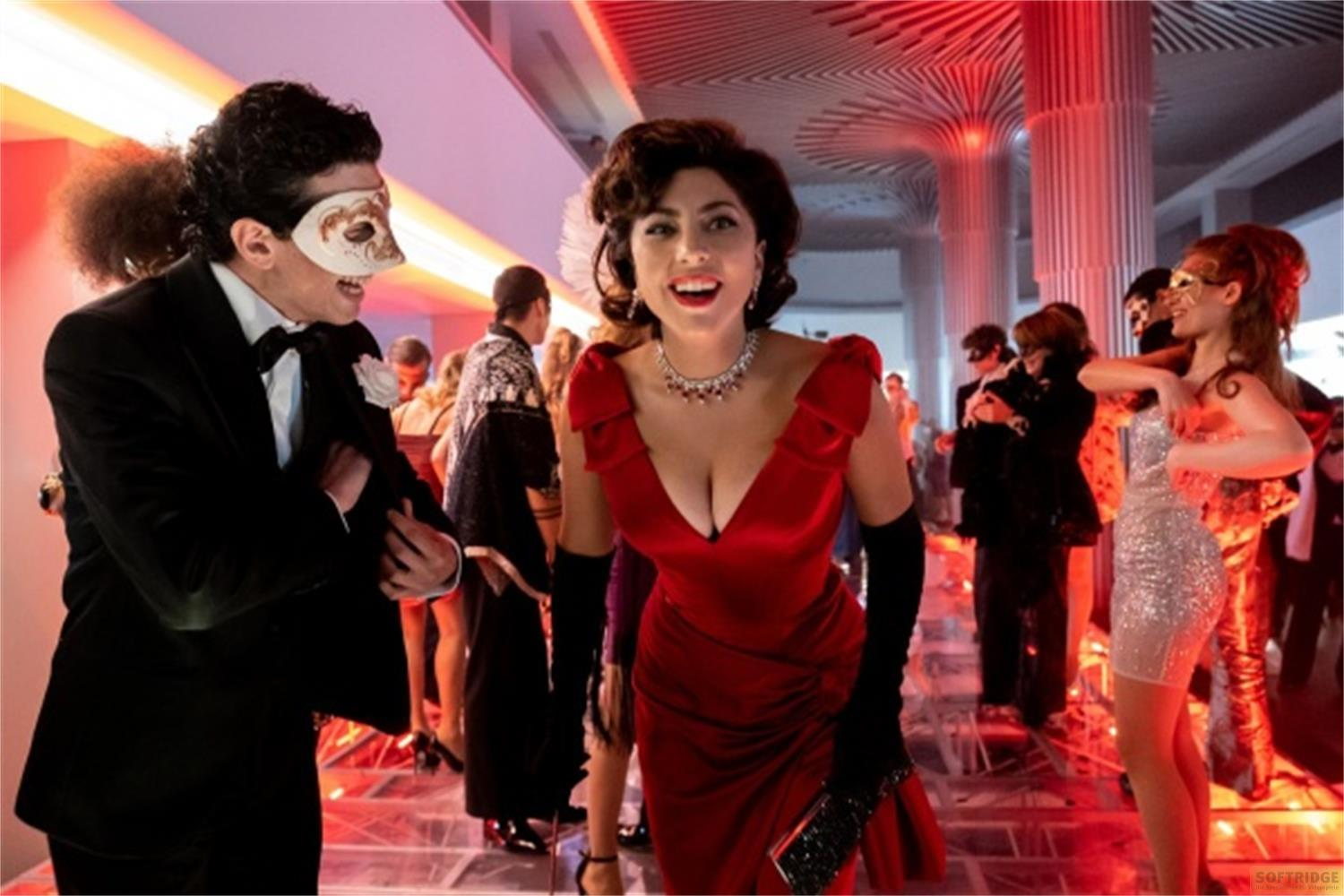 Persone in maschera e abiti da sera ballano a una festa con luci rosse.