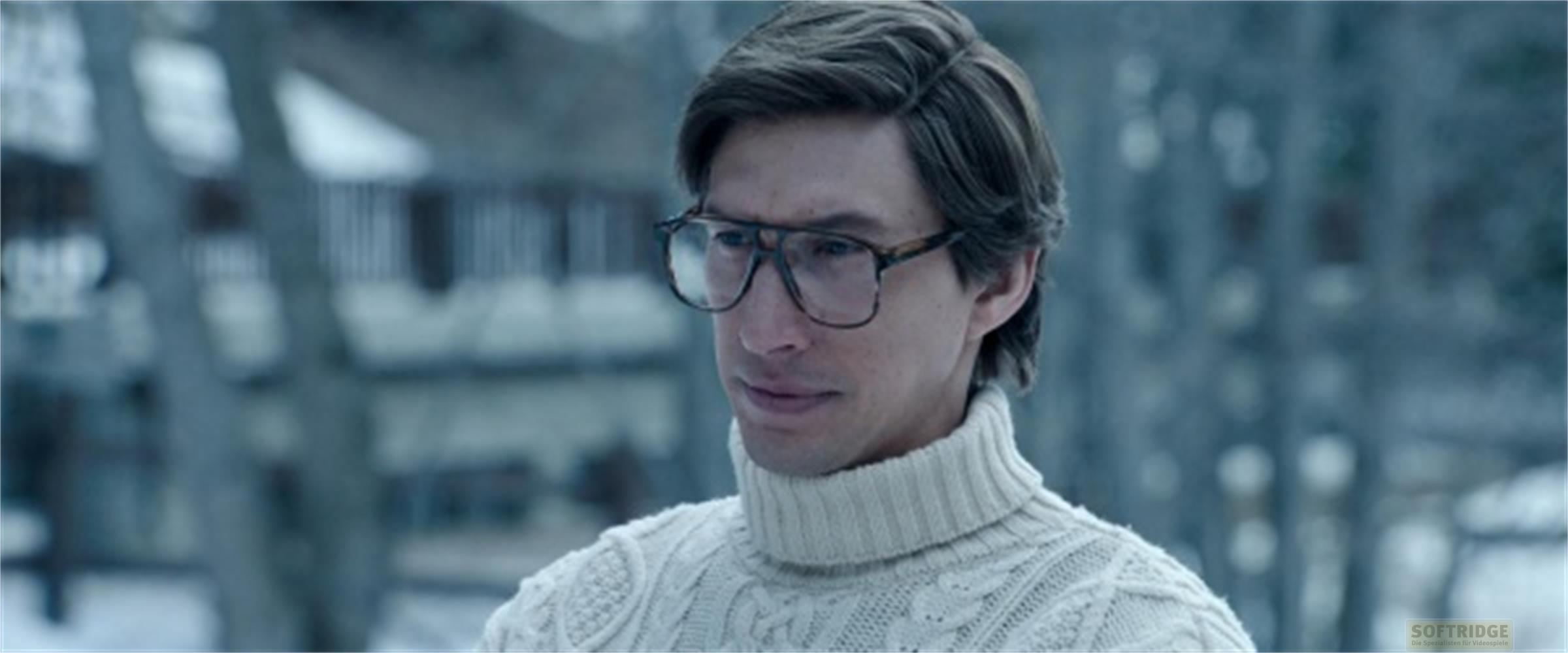 Uomo con occhiali indossa maglione a collo alto in ambiente innevato.