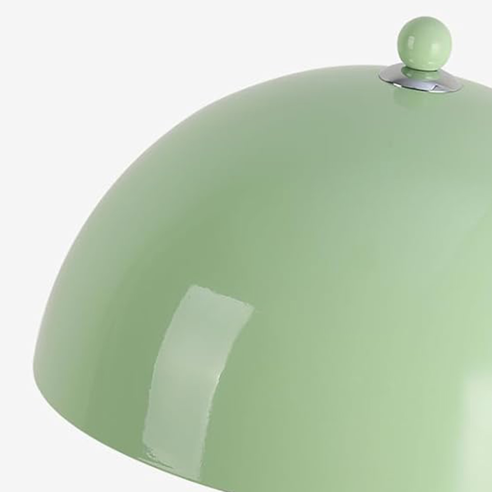 Pantalla de lámpara verde con pomo plateado y reflejos de luz.