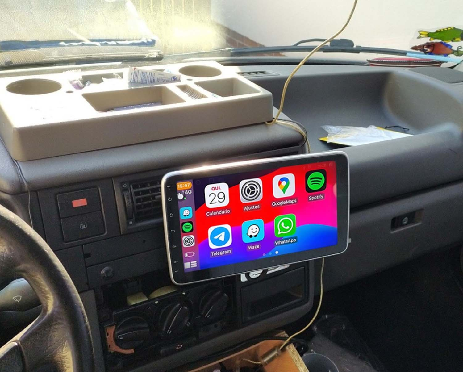 Ein Autoradio mit Touchscreen zeigt App-Symbole. Oben ist ein Organizer für Becherhalter.