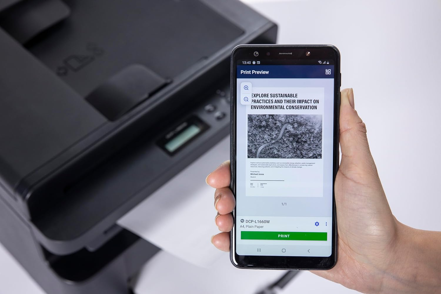 Ręka trzyma smartfon z podglądem wydruku badania środowiskowego obok drukarki.