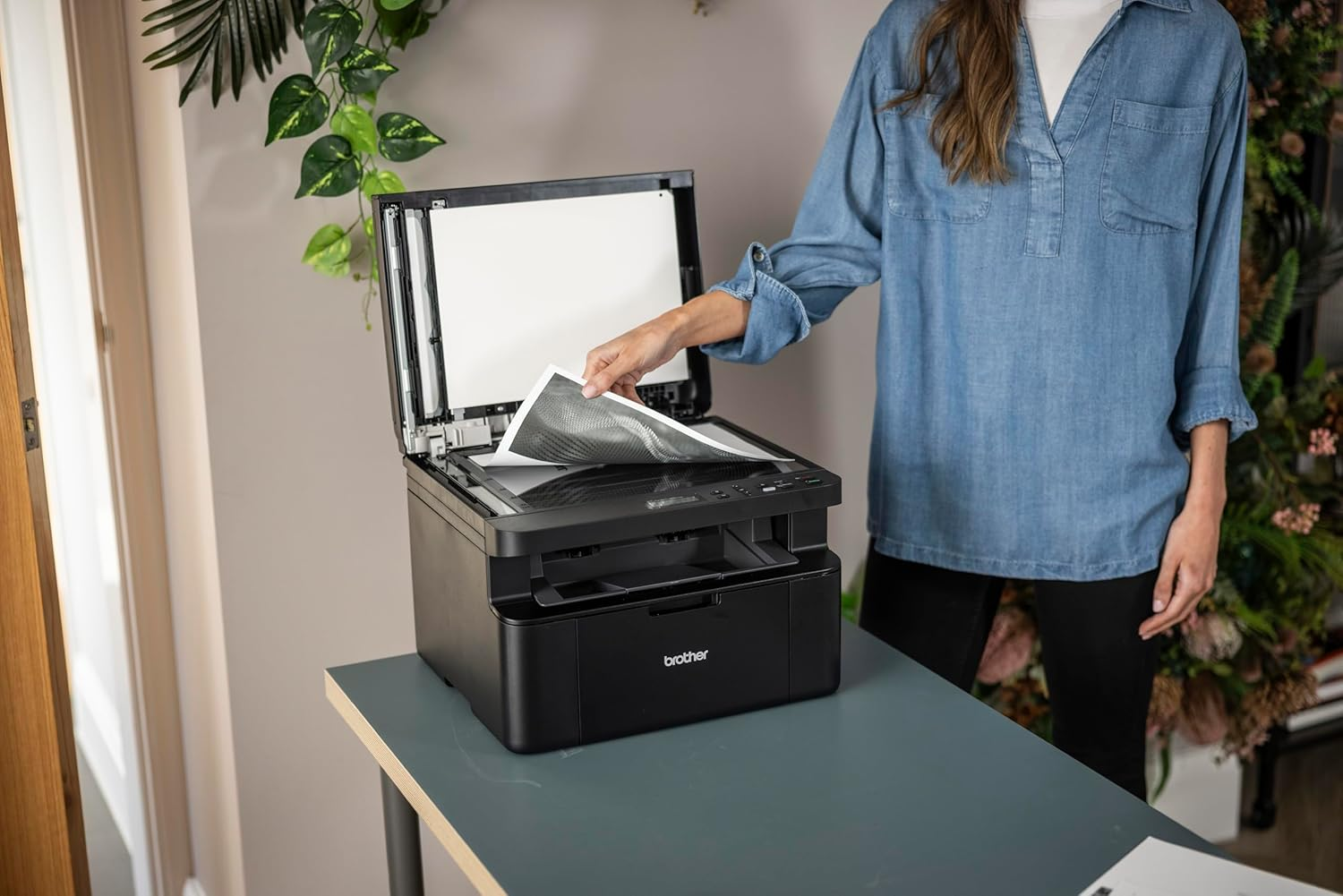 Eine Frau legt ein Dokument in einen Brother Drucker/Scanner.
