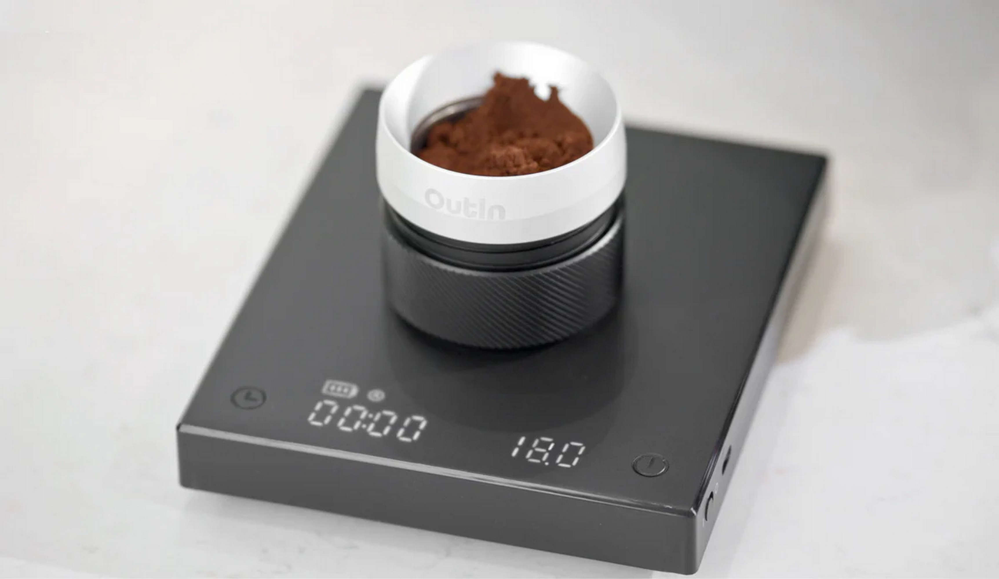 Czarna waga cyfrowa z pojemnikiem z kawą mieloną.