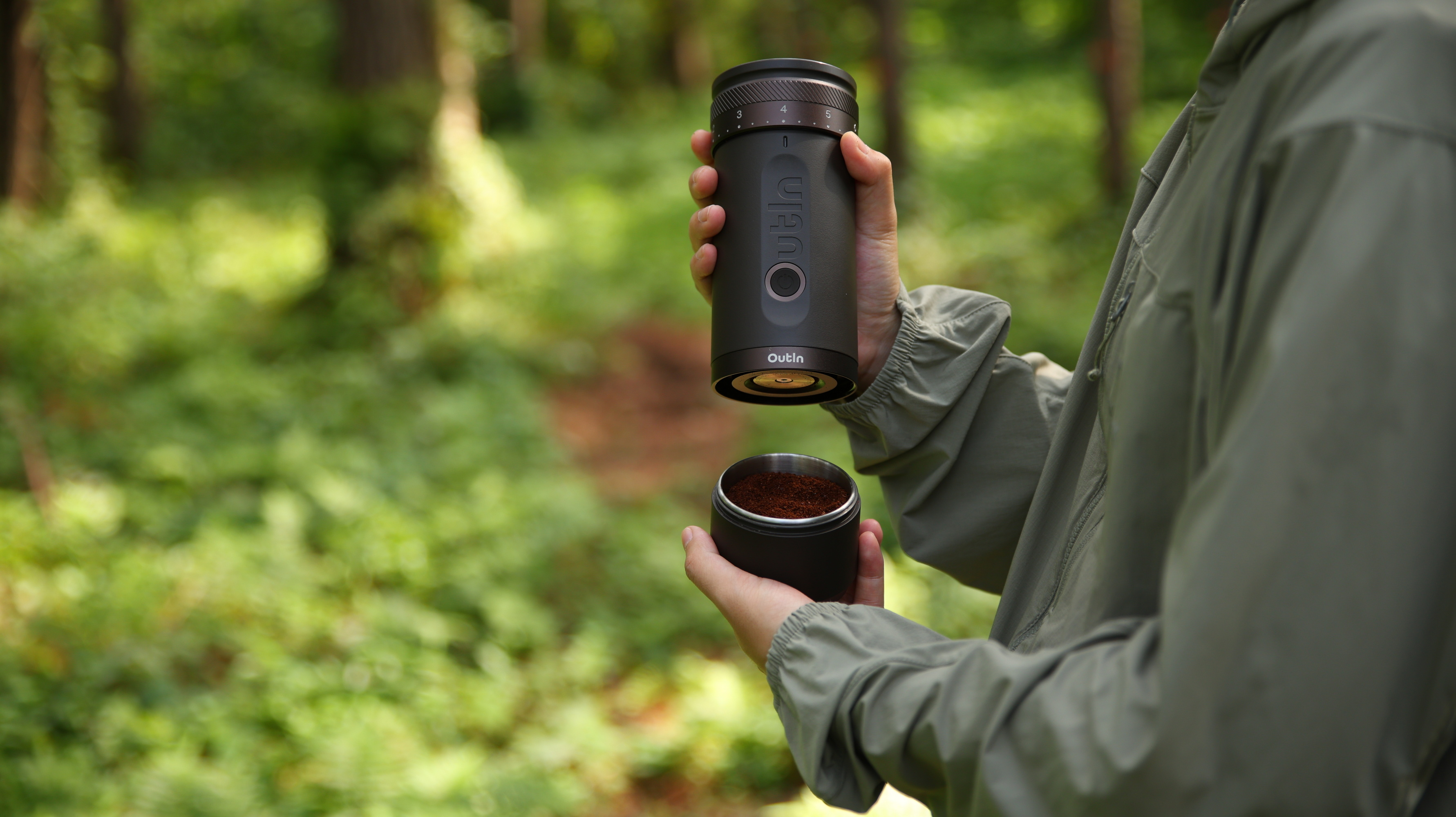 Osoba trzyma ekspres do kawy i kawę mieloną w lesie.