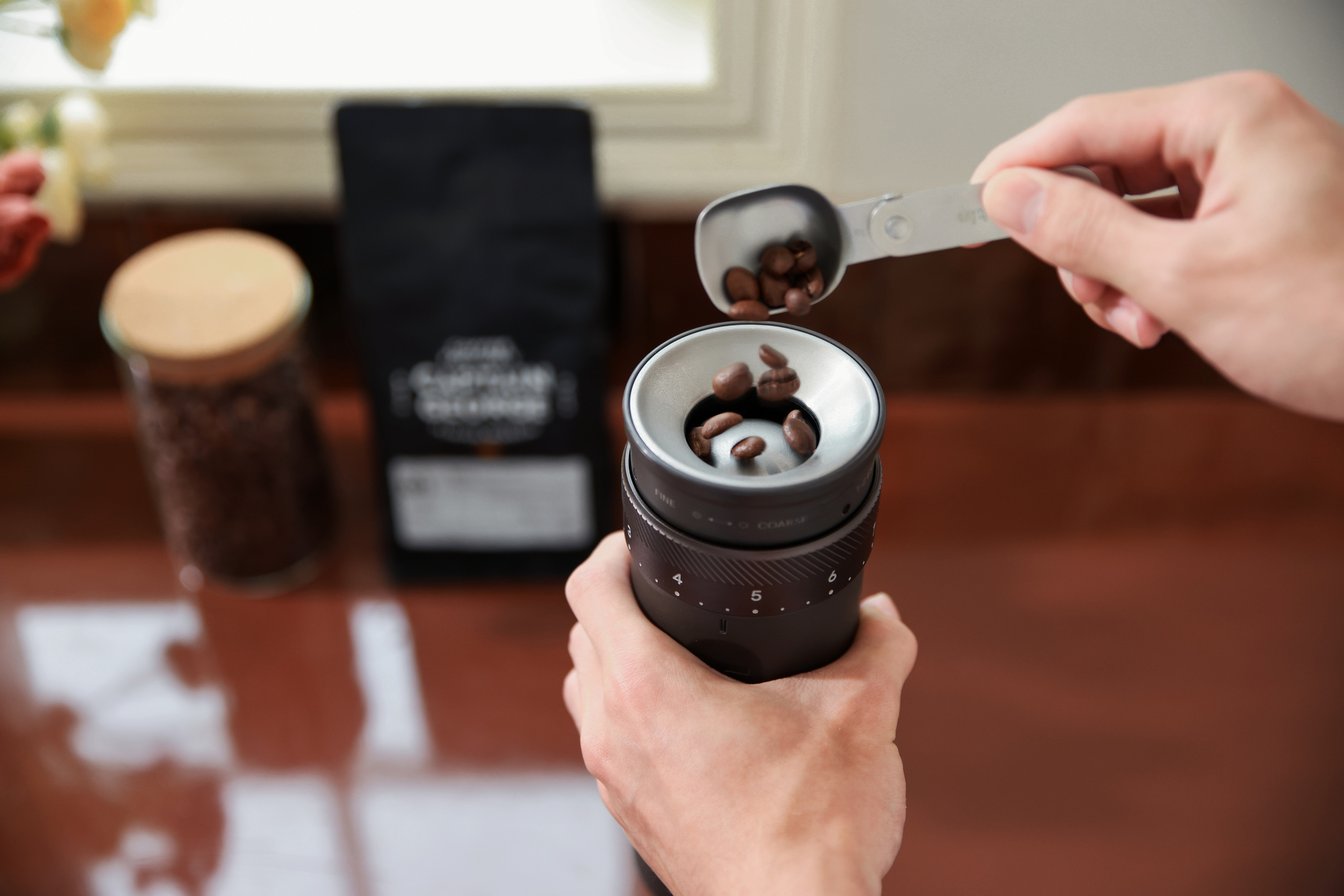 Ziarna kawy są wsypywane z łyżki do młynka do kawy.