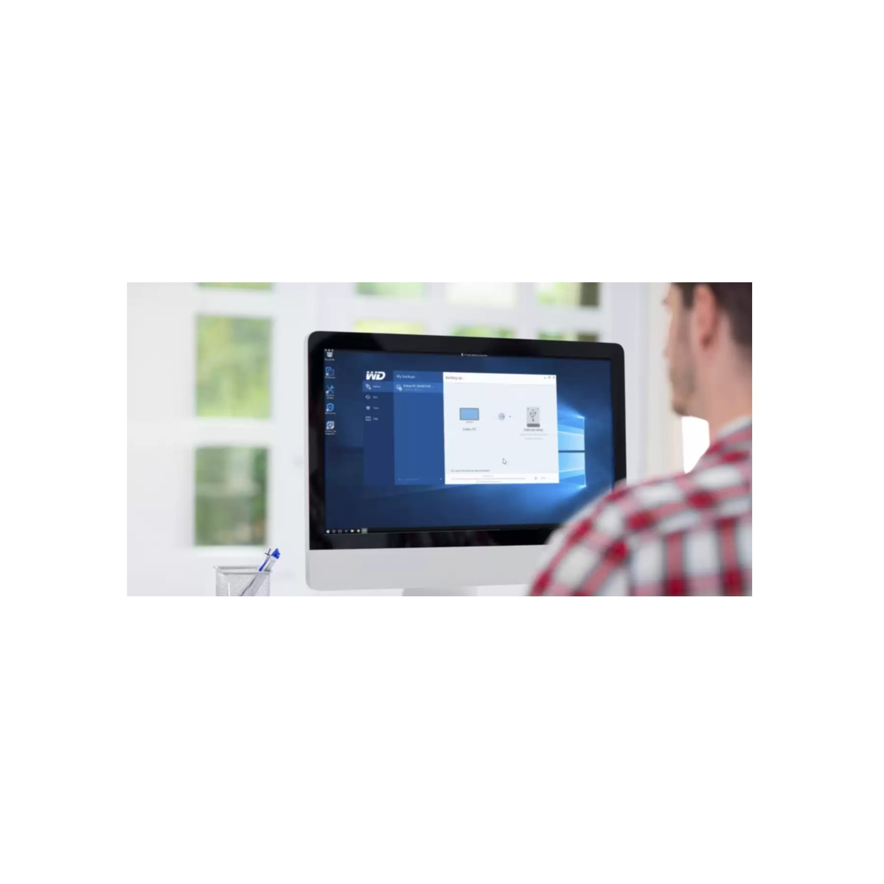 Mężczyzna patrzy na ekran komputera z oprogramowaniem do tworzenia kopii zapasowych.