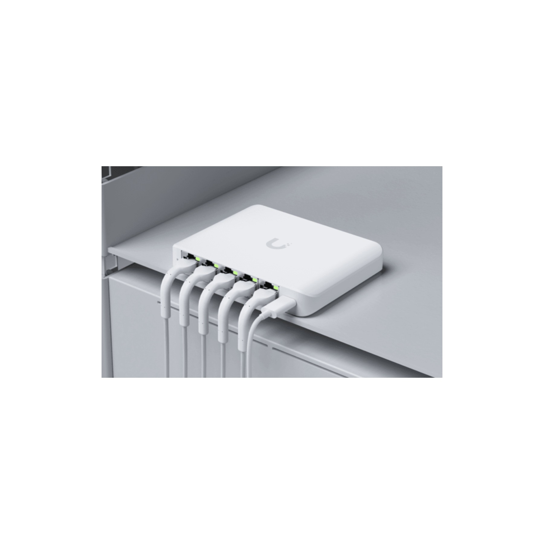 Een witte netwerkswitch met vijf aangesloten witte kabels op een grijze plank.