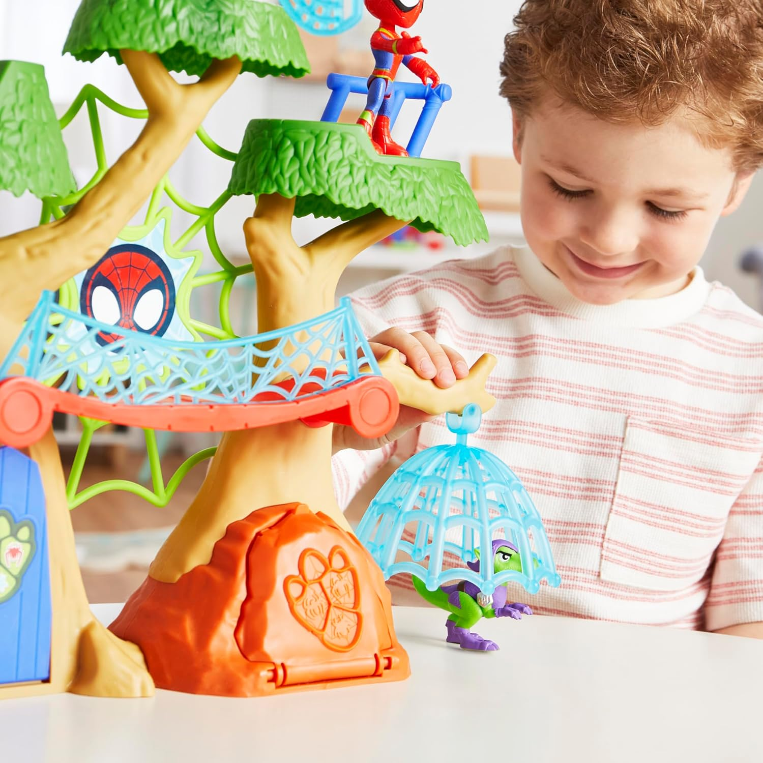 Un ragazzo gioca con una casa sull'albero giocattolo di Spiderman con action figure.