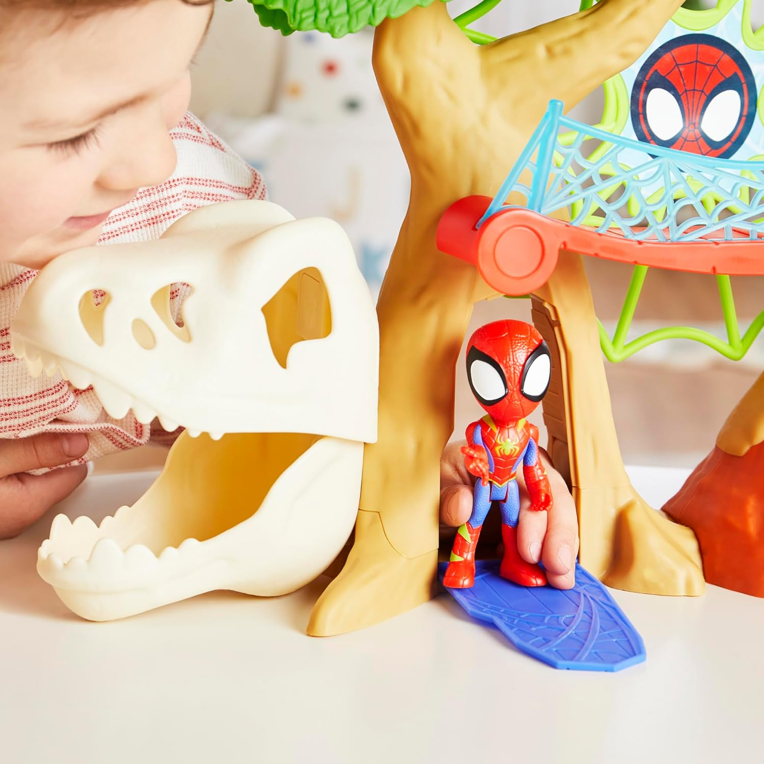 Un bambino guarda un playset di Spiderman con teschio di dinosauro.