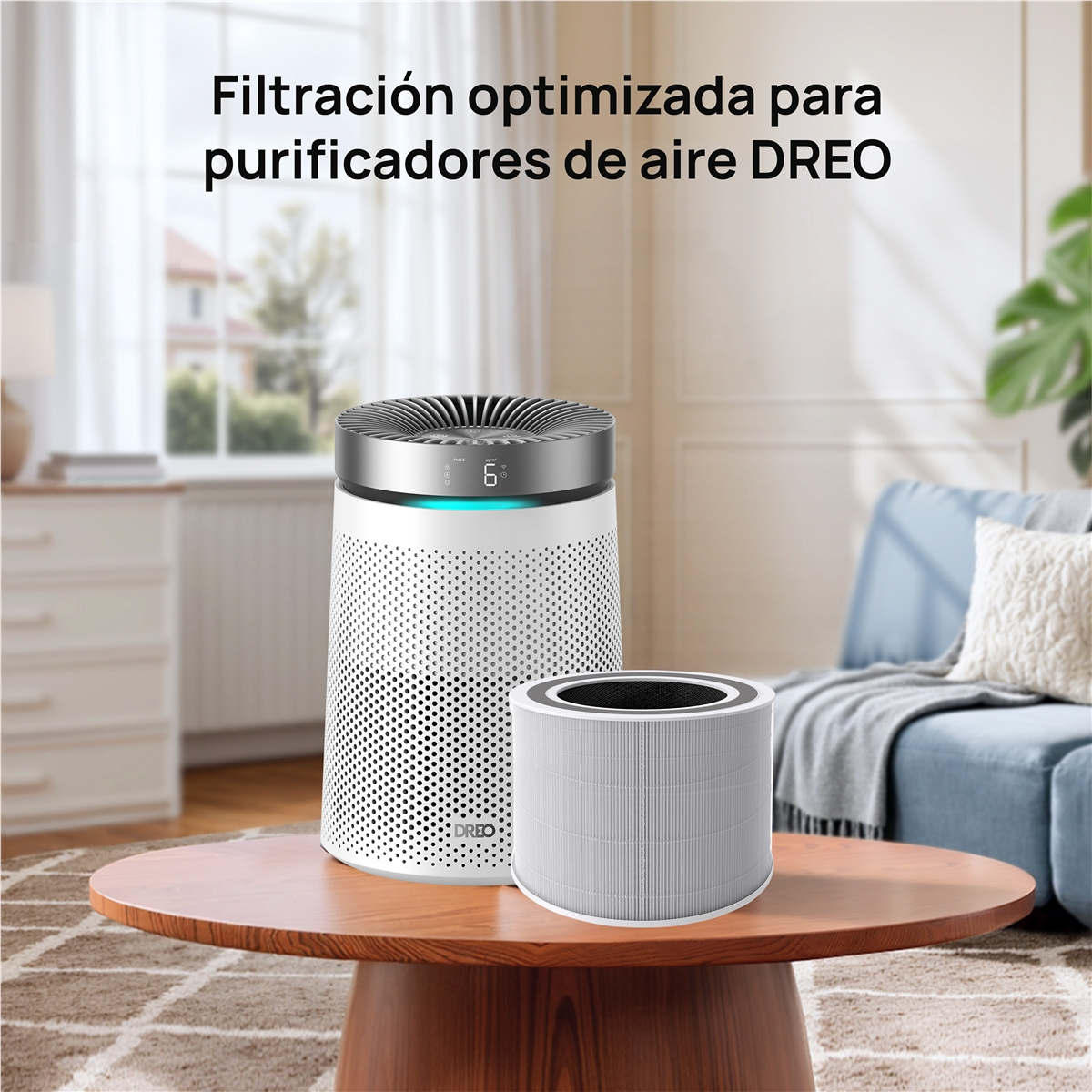 Un purificador de aire blanco con tapa plateada y un filtro de repuesto en una mesa de madera.