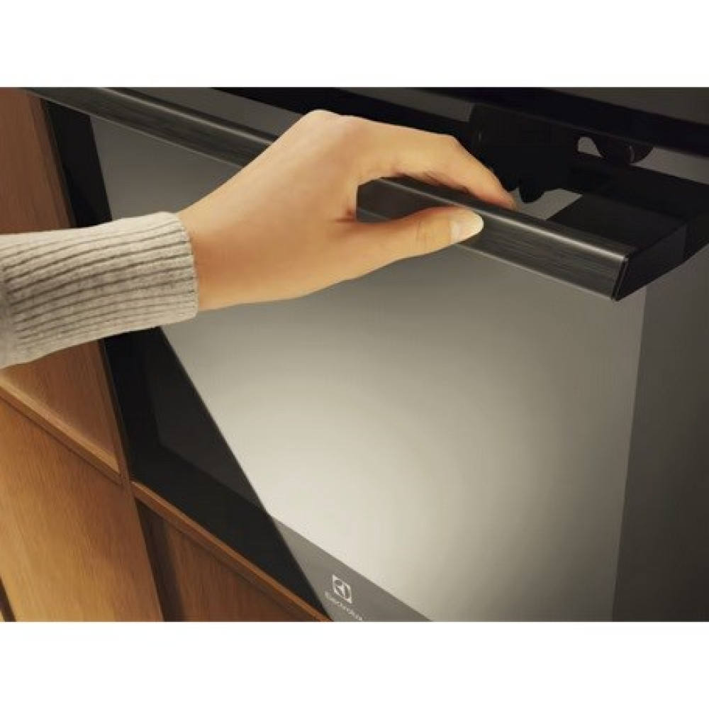 Dłoń w swetrze otwiera ciemną szufladę z uchwytem.