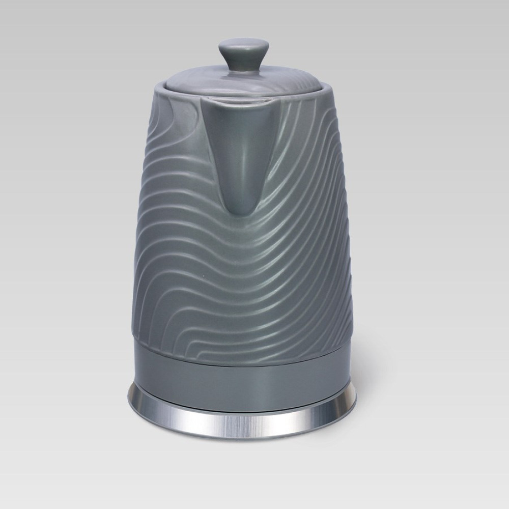 Szara czajnik z falistym wzorem i srebrną podstawą.