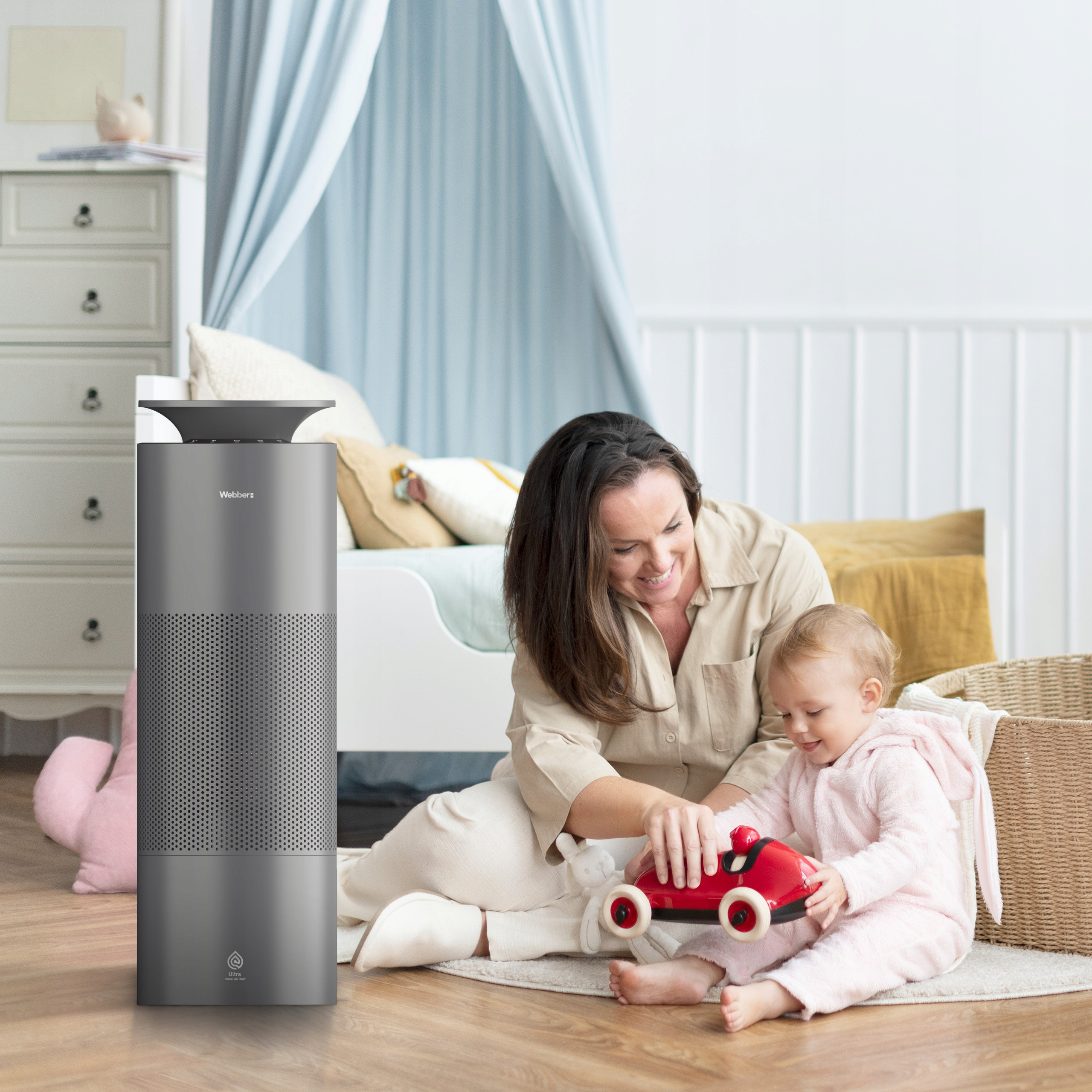 Matka i dziecko bawią się samochodzikiem w pokoju dziecięcym obok oczyszczacza powietrza.