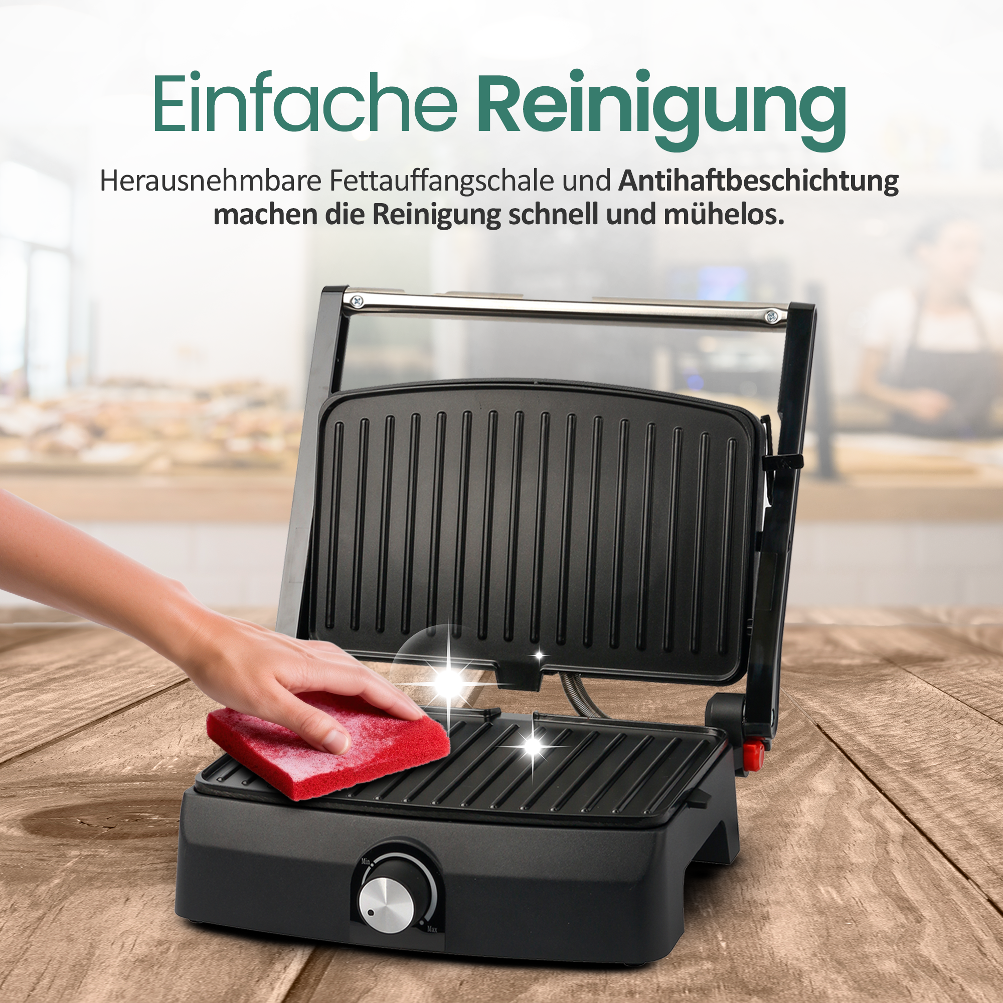 Eine Hand reinigt einen schwarzen Kontaktgrill mit einem roten Schwamm.