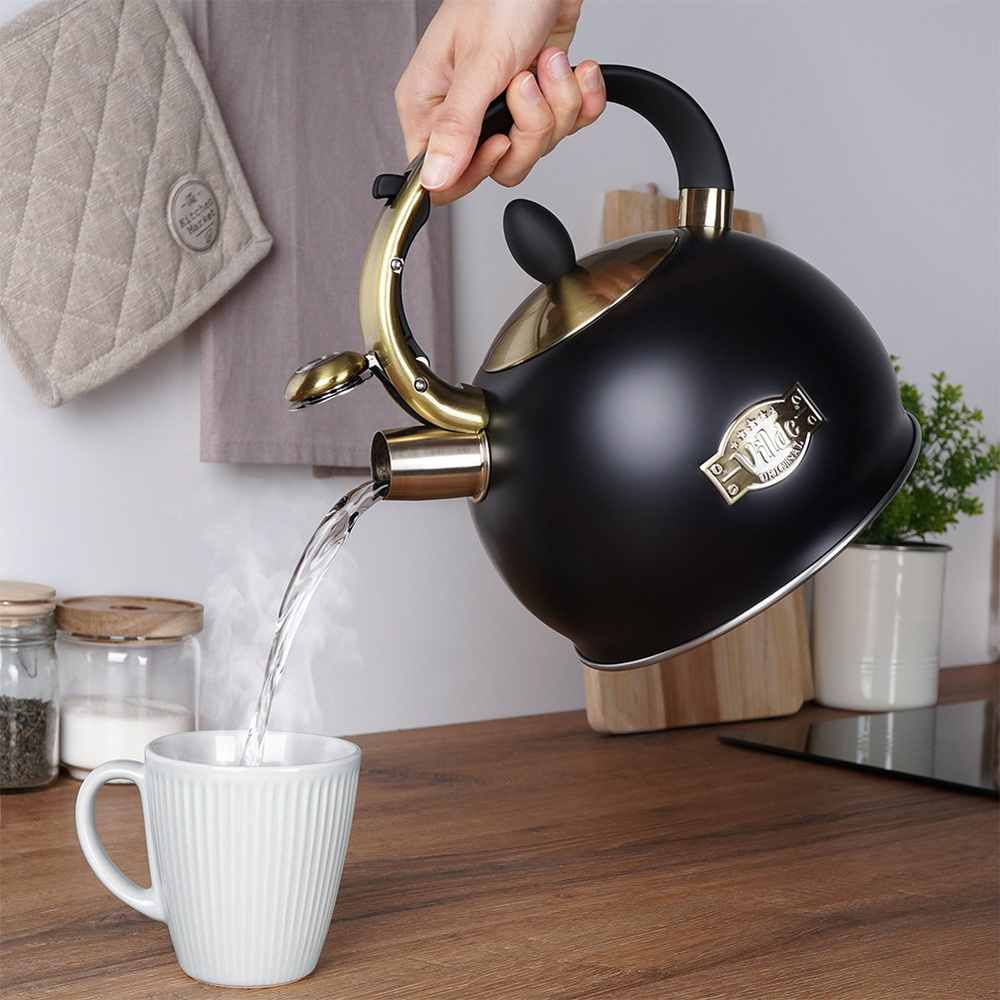 Una tetera negra con detalles dorados vierte agua en una taza blanca. Humo.