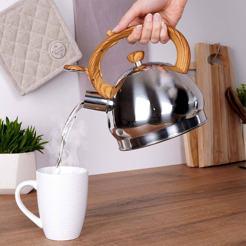 Una mano vierte agua caliente de una tetera brillante en una taza blanca.