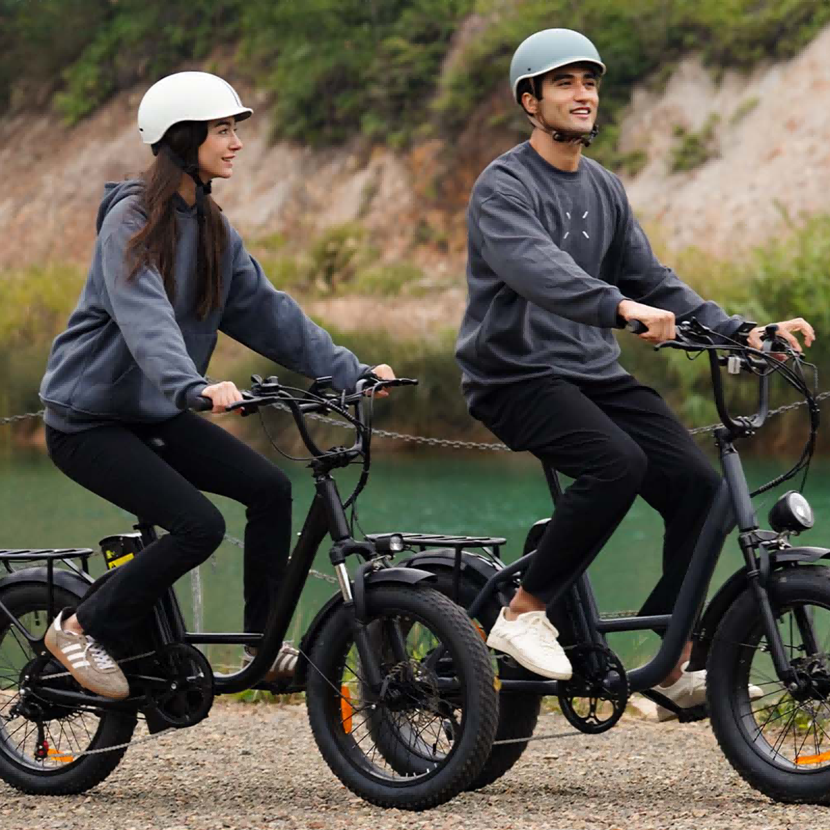 Dwie osoby w kaskach jadą rowerami elektrycznymi nad zbiornikiem wodnym.