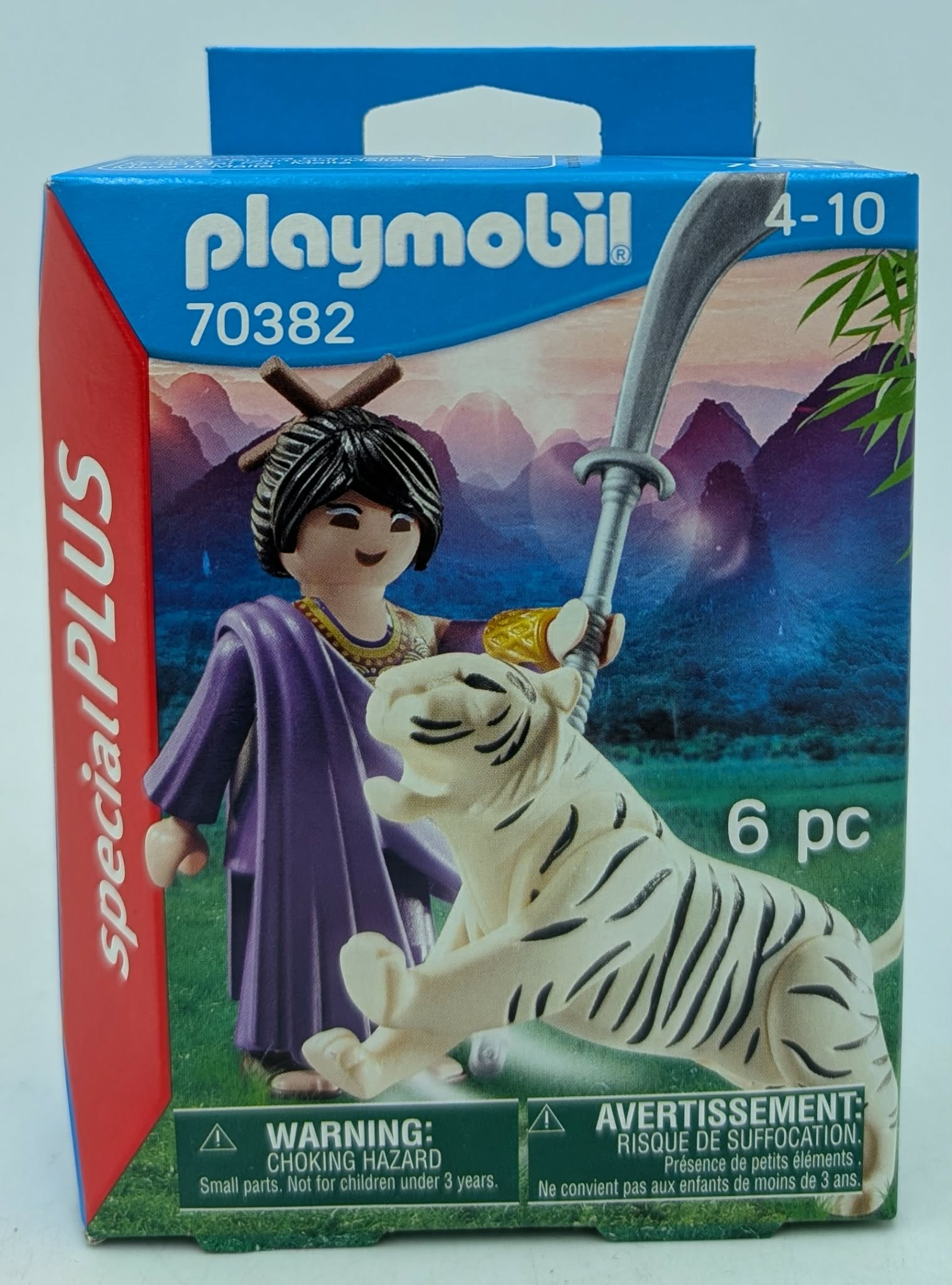Playmobil box with figure and white tiger against mountain backdrop.