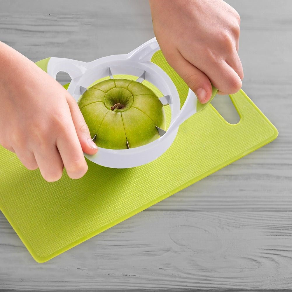 Manzana verde cortada por manos con un cortador de manzanas blanco.