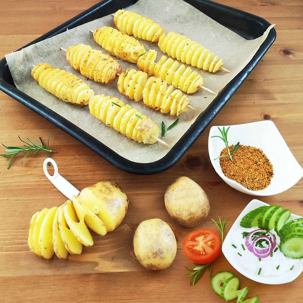 Patatas en espiral en brochetas en una bandeja para hornear con condimento.