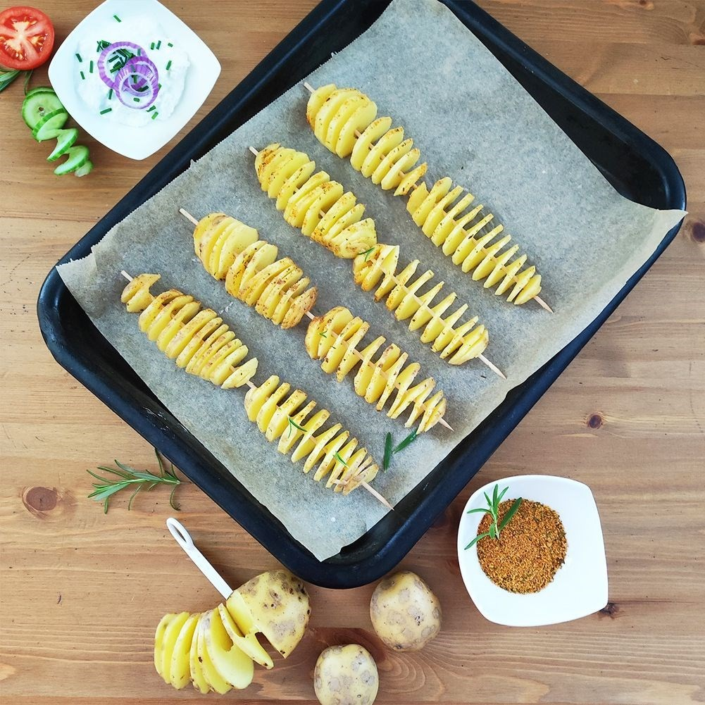 Papas en espiral en brochetas sobre bandeja para hornear con especias y dip