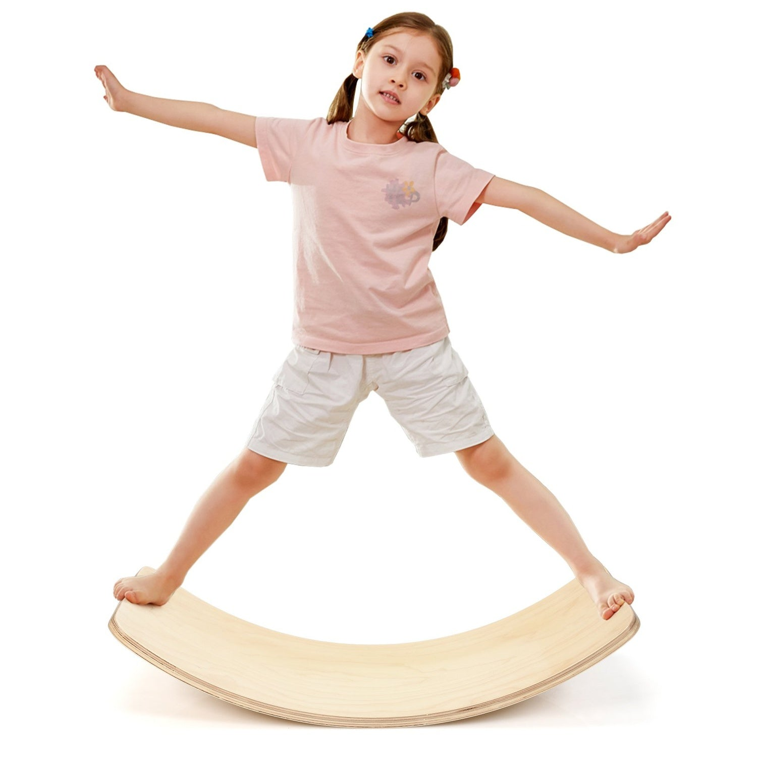 Una niña pequeña se balancea en una tabla de equilibrio de madera.
