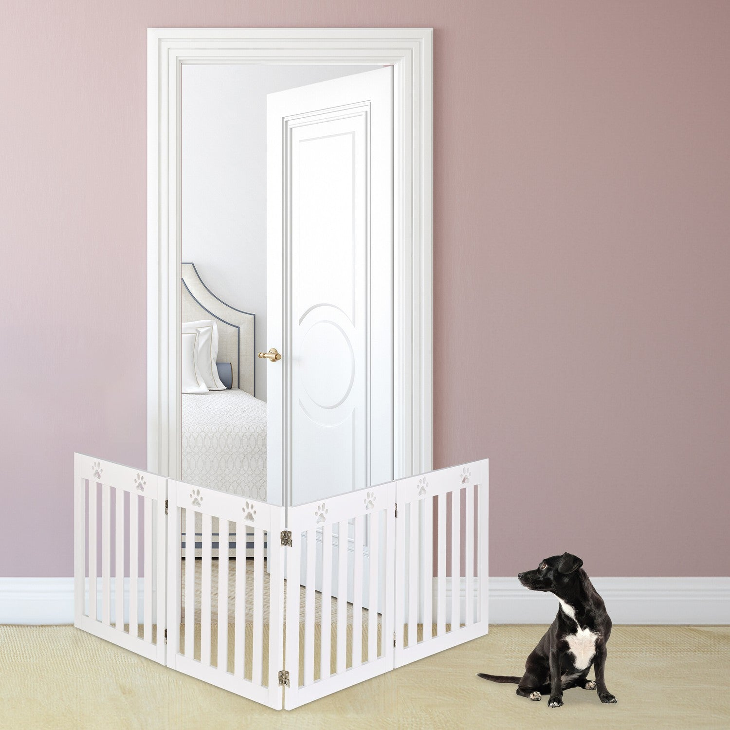Un perro negro se sienta ante una barrera blanca que bloquea una puerta abierta a un dormitorio.