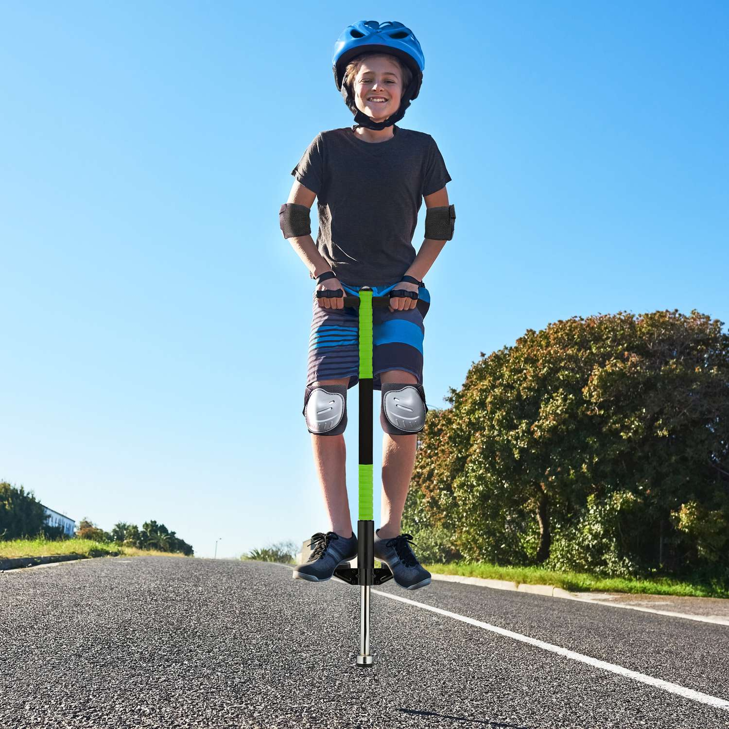 Un niño con equipo de protección en un saltador verde en una carretera.