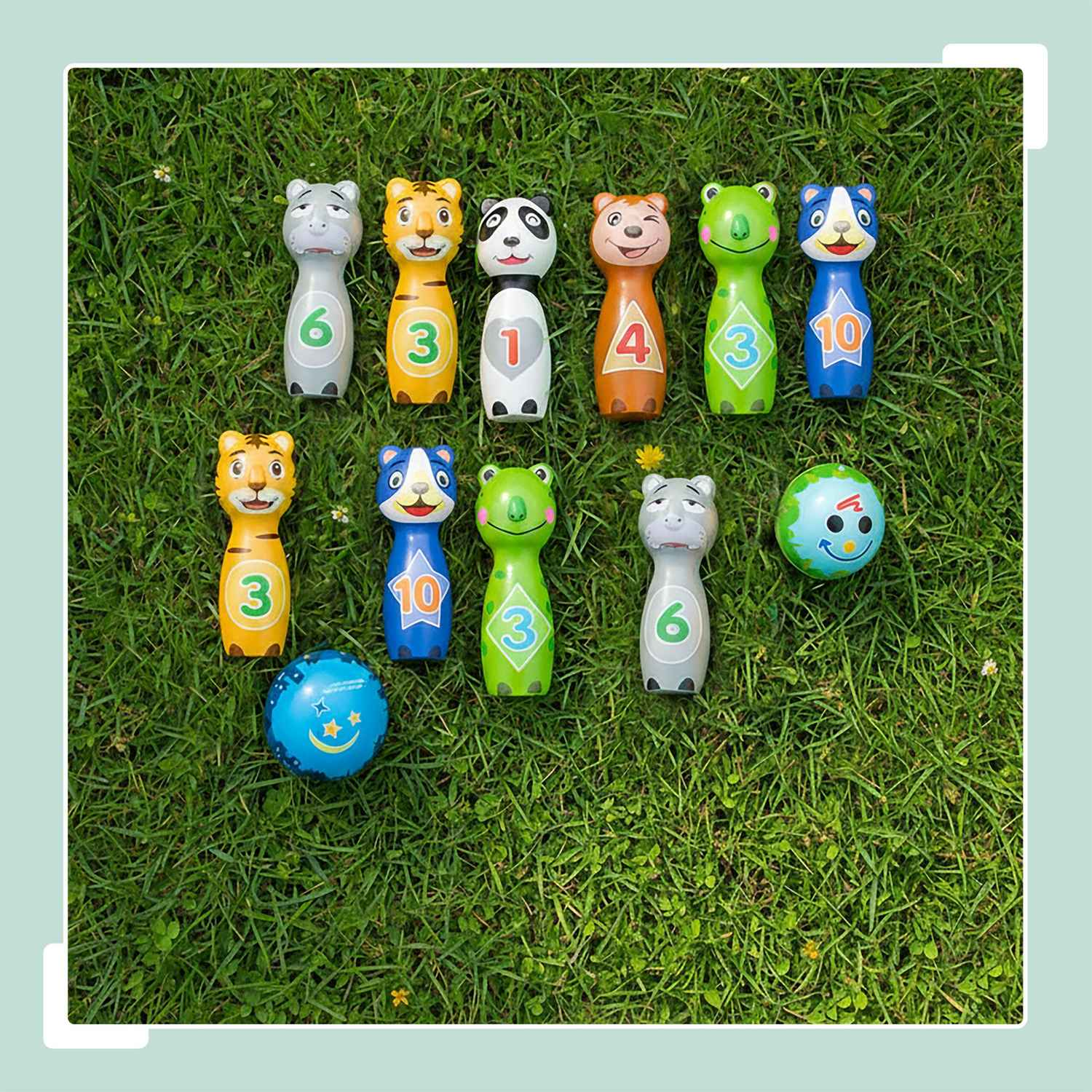 Diez bolos de animales numerados y dos pelotas sobre hierba.