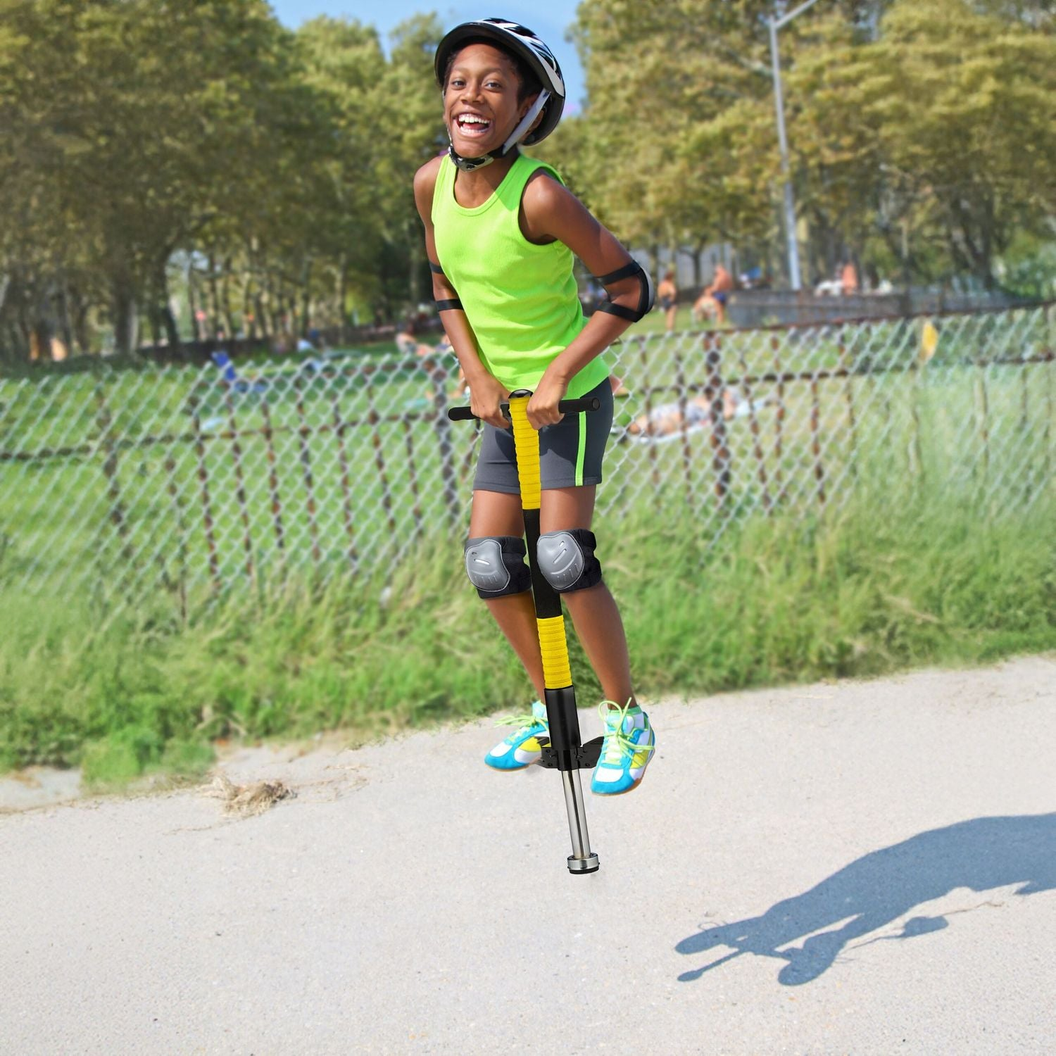 Un niño en un pogo stick, con casco y rodilleras, salta al aire libre.