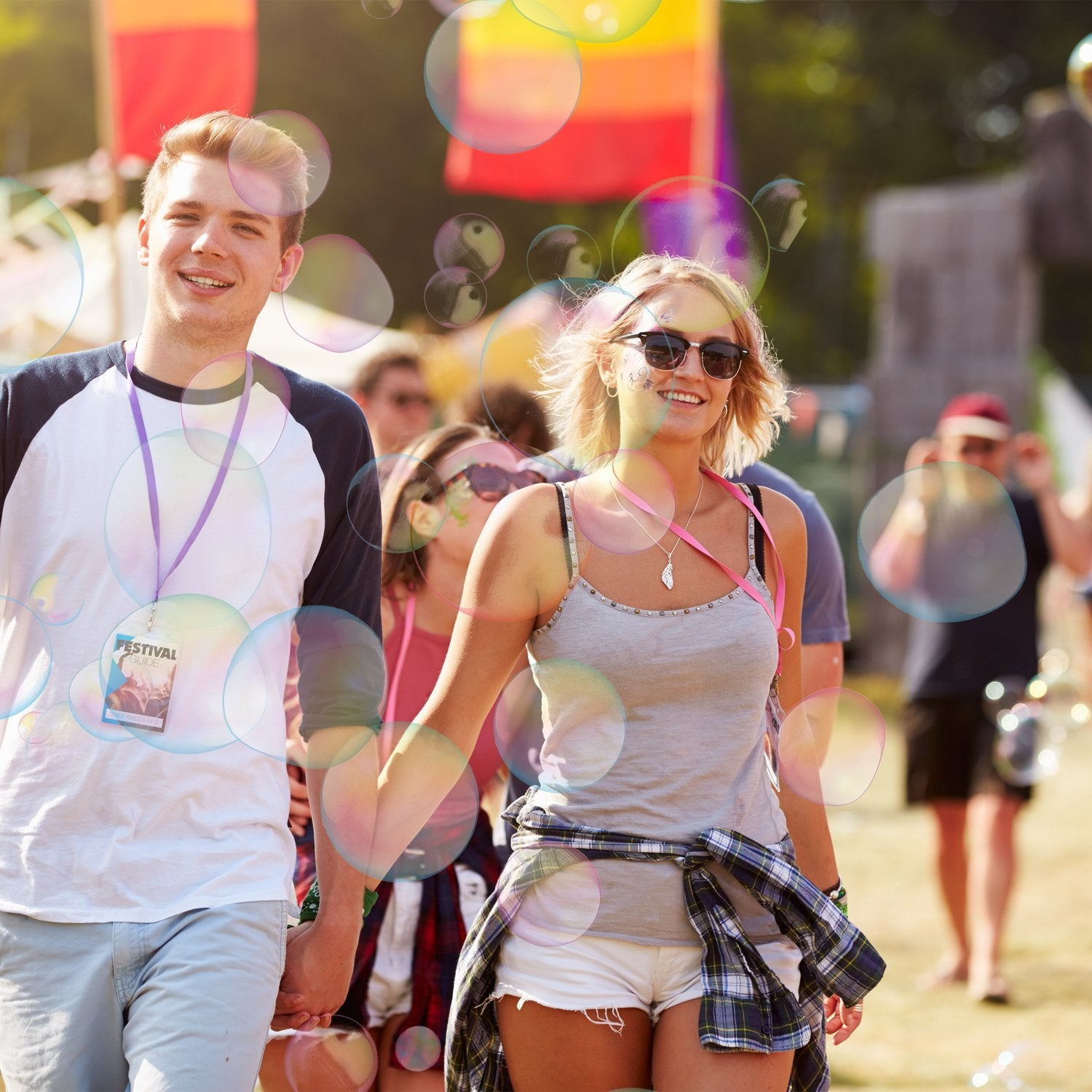 Una pareja joven se toma de la mano en un festival, rodeada de burbujas.