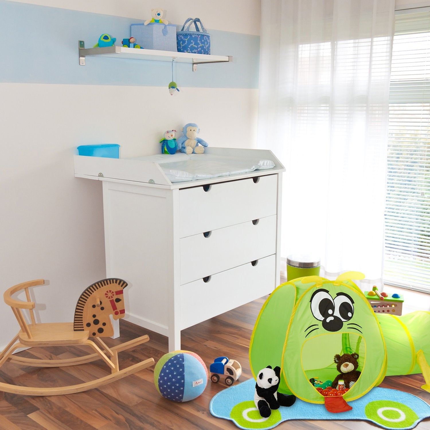 Habitación infantil con cambiador, caballito de madera y carpa de juegos.