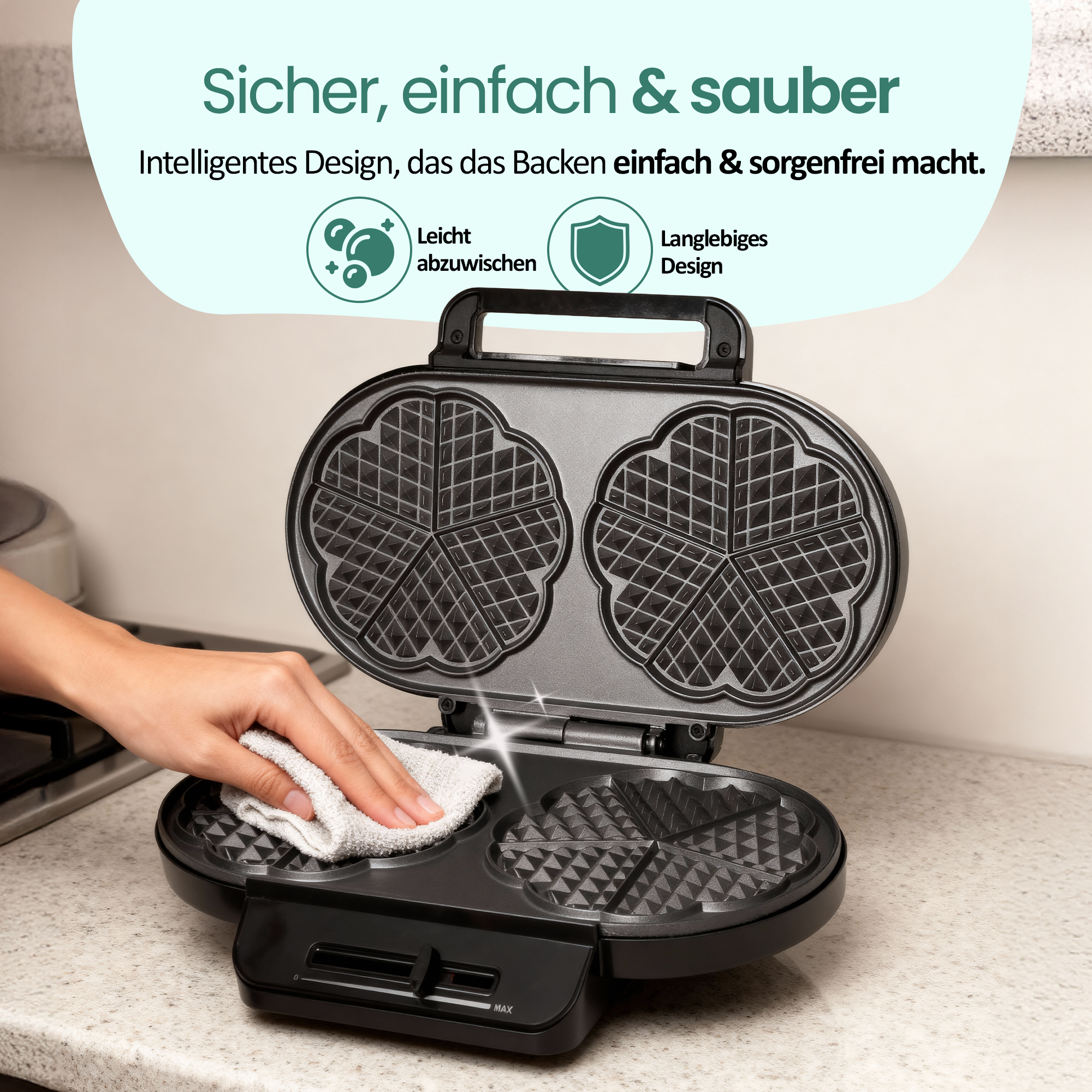 Eine Hand wischt eine schwarze Waffelform mit einem weißen Tuch ab.