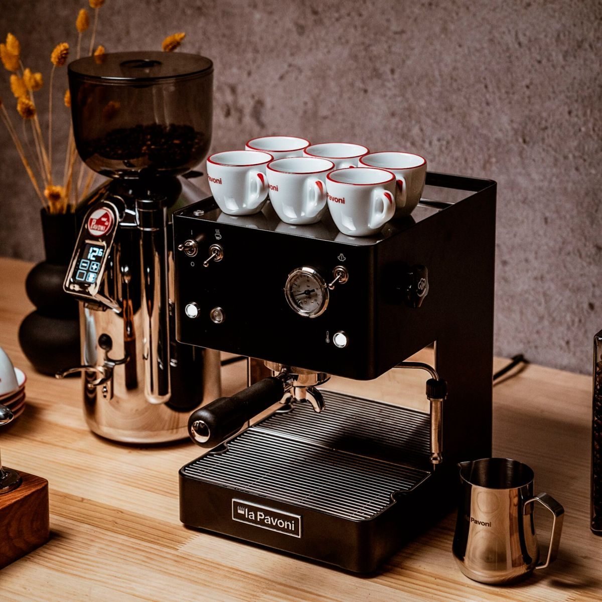 Espressomaschine mit Kaffeemühle, Tassen, Milchkännchen und Bohnen.