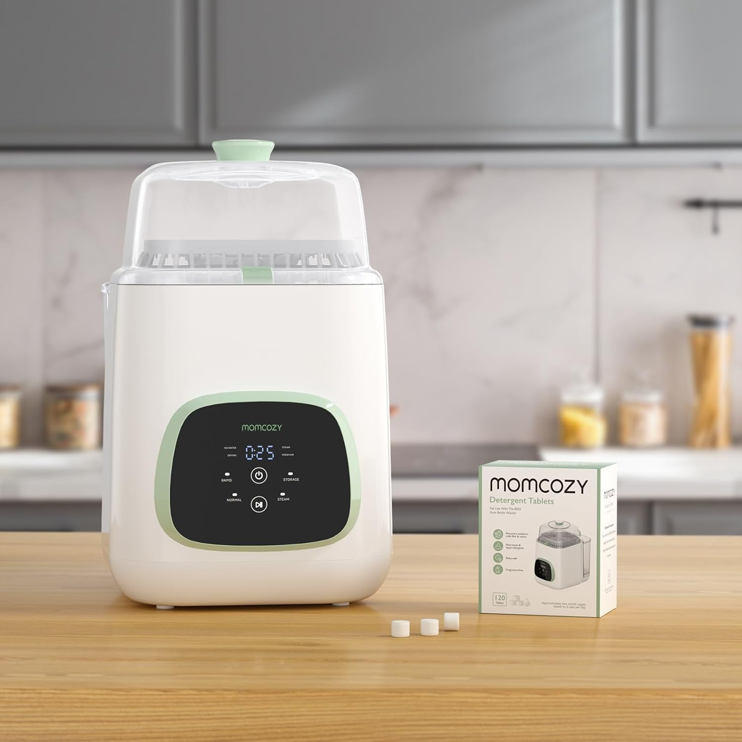 Un stérilisateur blanc pour biberons avec des accents verts et une boîte de tablettes.