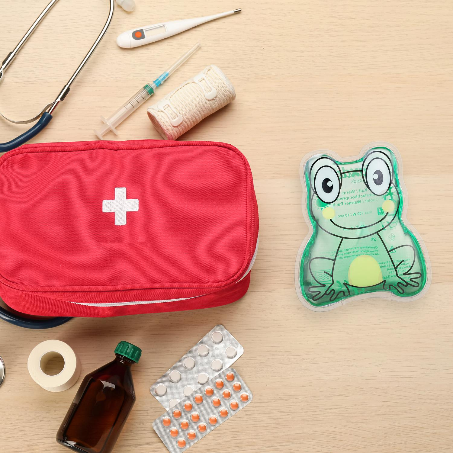 Un botiquín rojo con suministros médicos y una bolsa de calor con forma de rana.