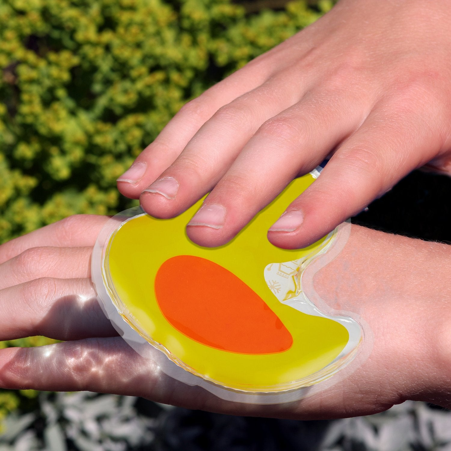 Compresa de gel con forma de pato en mano. Compresa de gel tiene cuerpo amarillo y pico naranja.