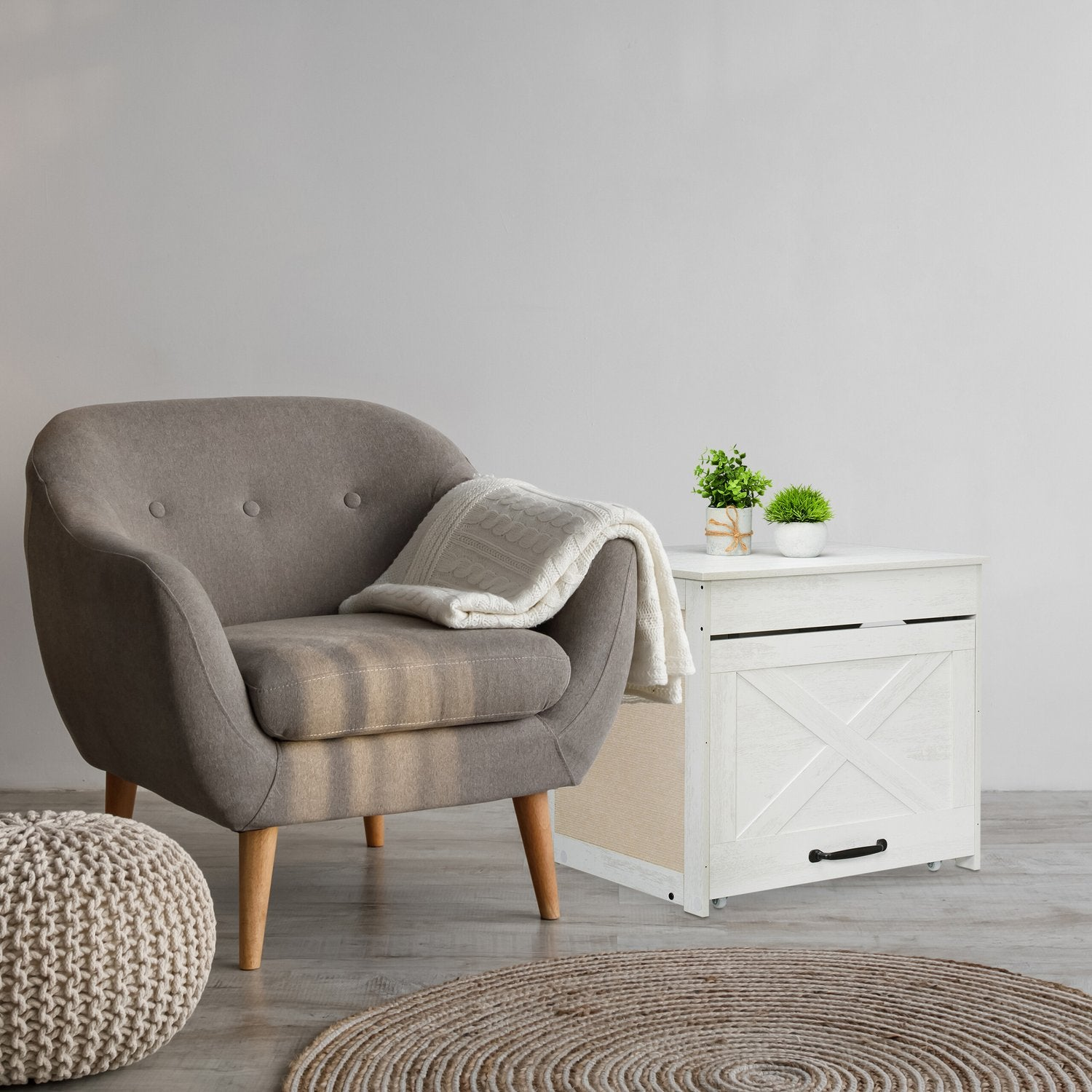 Butaca gris con manta junto a mesa auxiliar blanca con plantas.