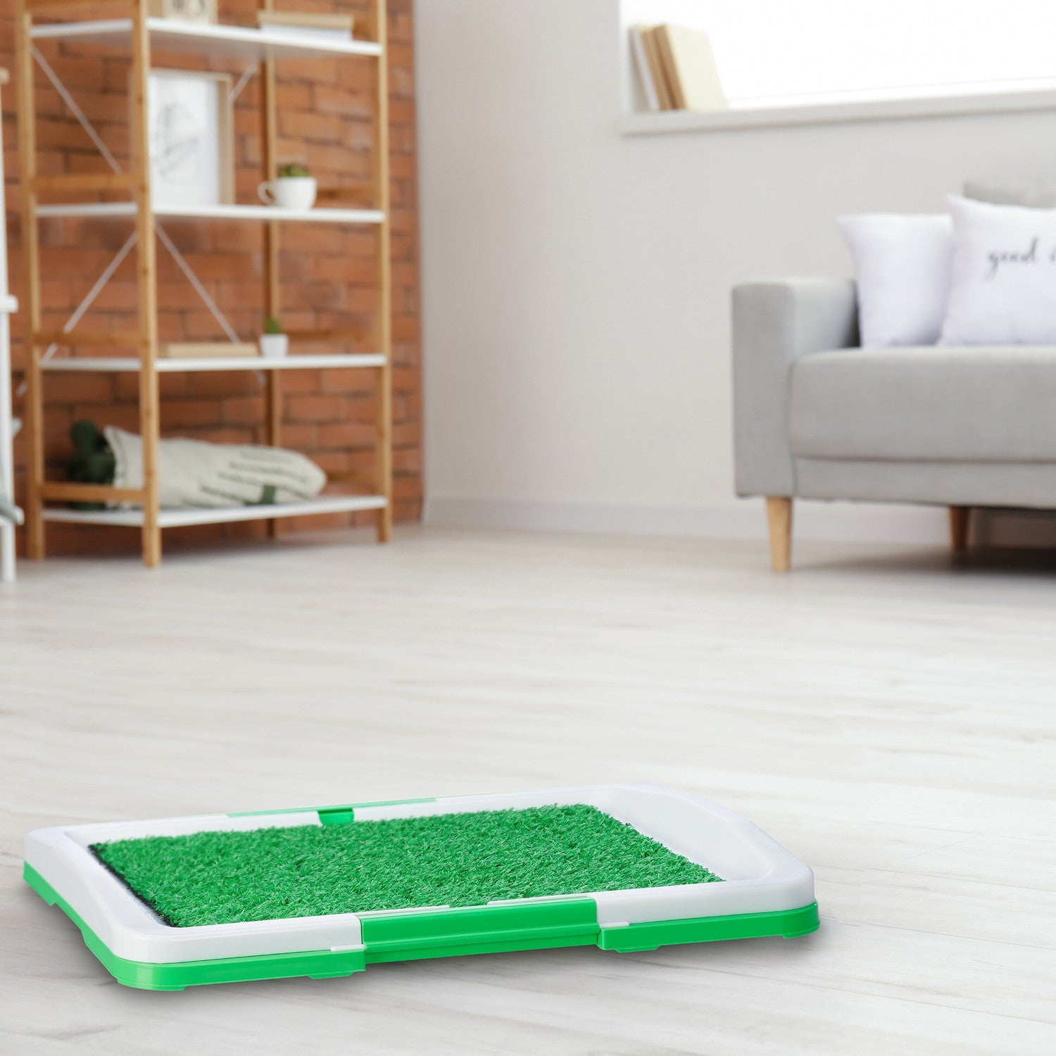 Bandeja verde de césped artificial para mascotas en suelo de madera.