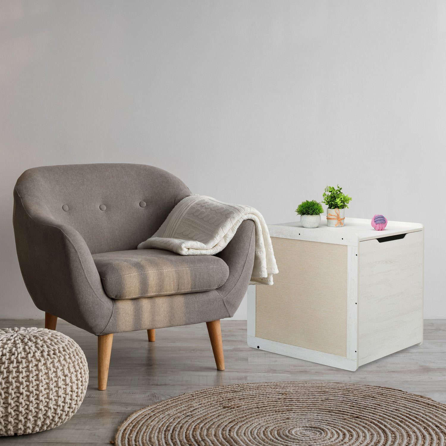 Un sillón gris junto a una mesita auxiliar blanca con plantas y una pelota.