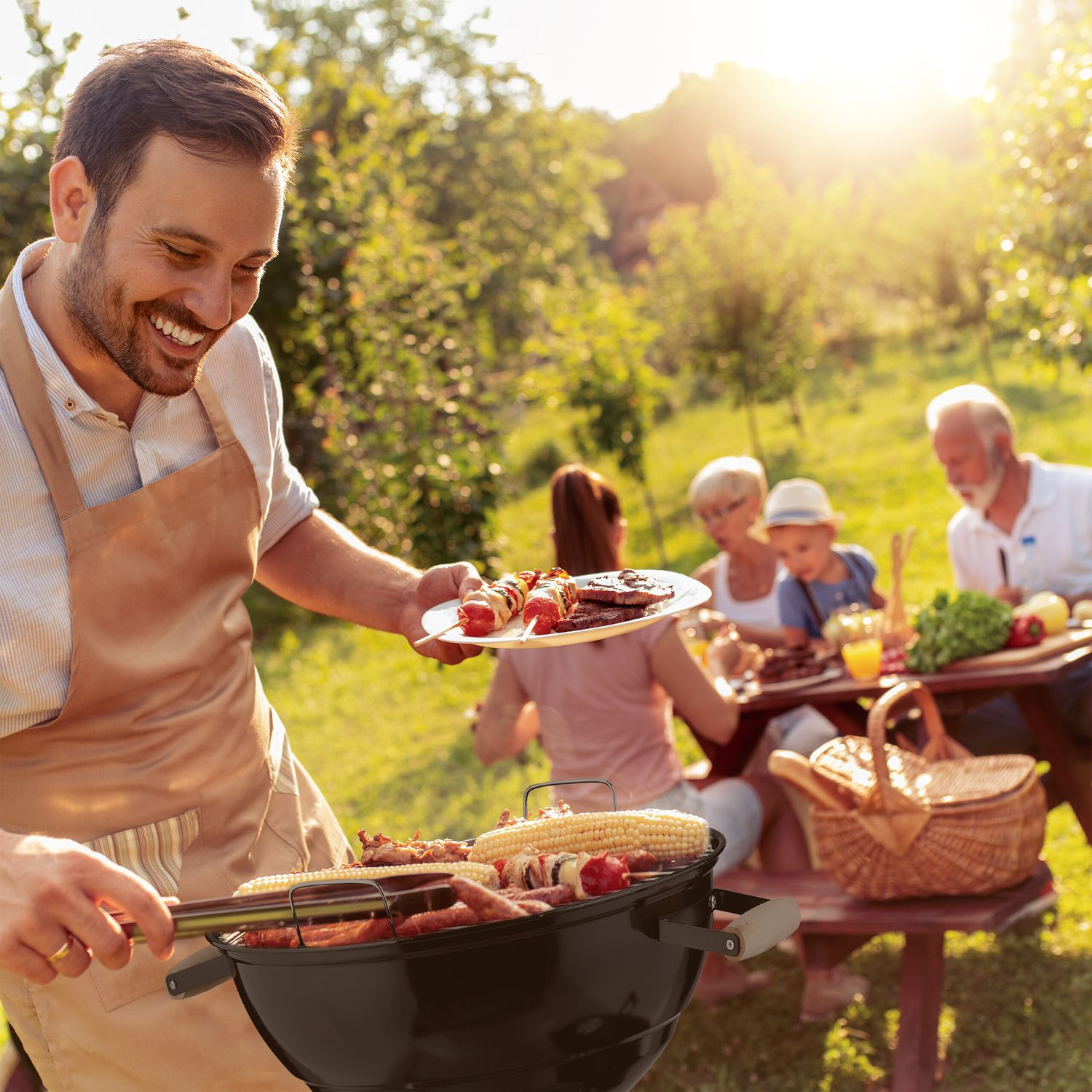 Hombre asando comida al aire libre con la familia. Día soleado.