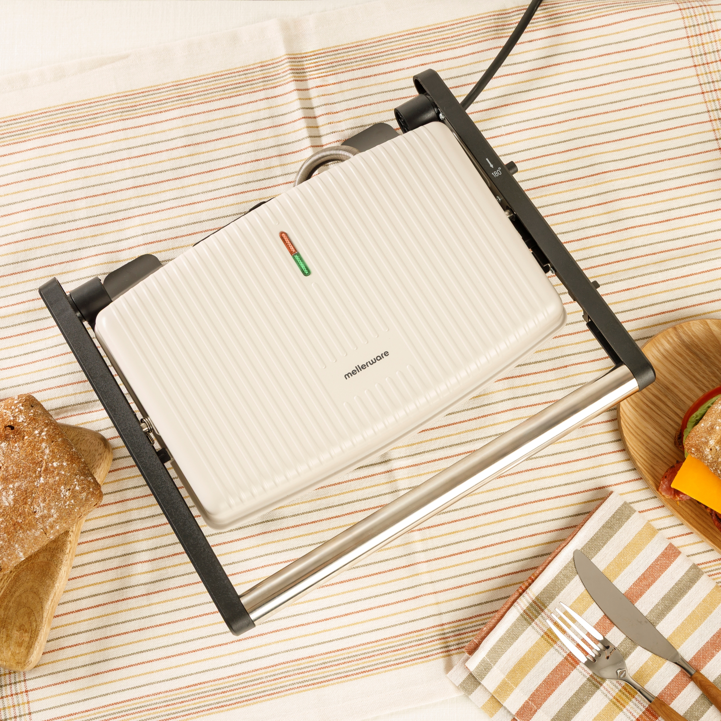 Una sandwichiera aperta con fette di pane e un sandwich nelle vicinanze.