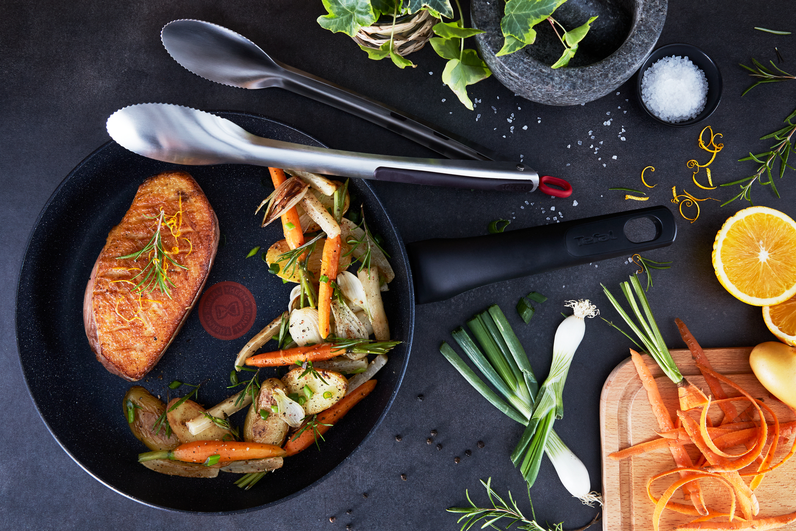 Pechuga de pato sellada con verduras de raíz en sartén, con ingredientes cerca.