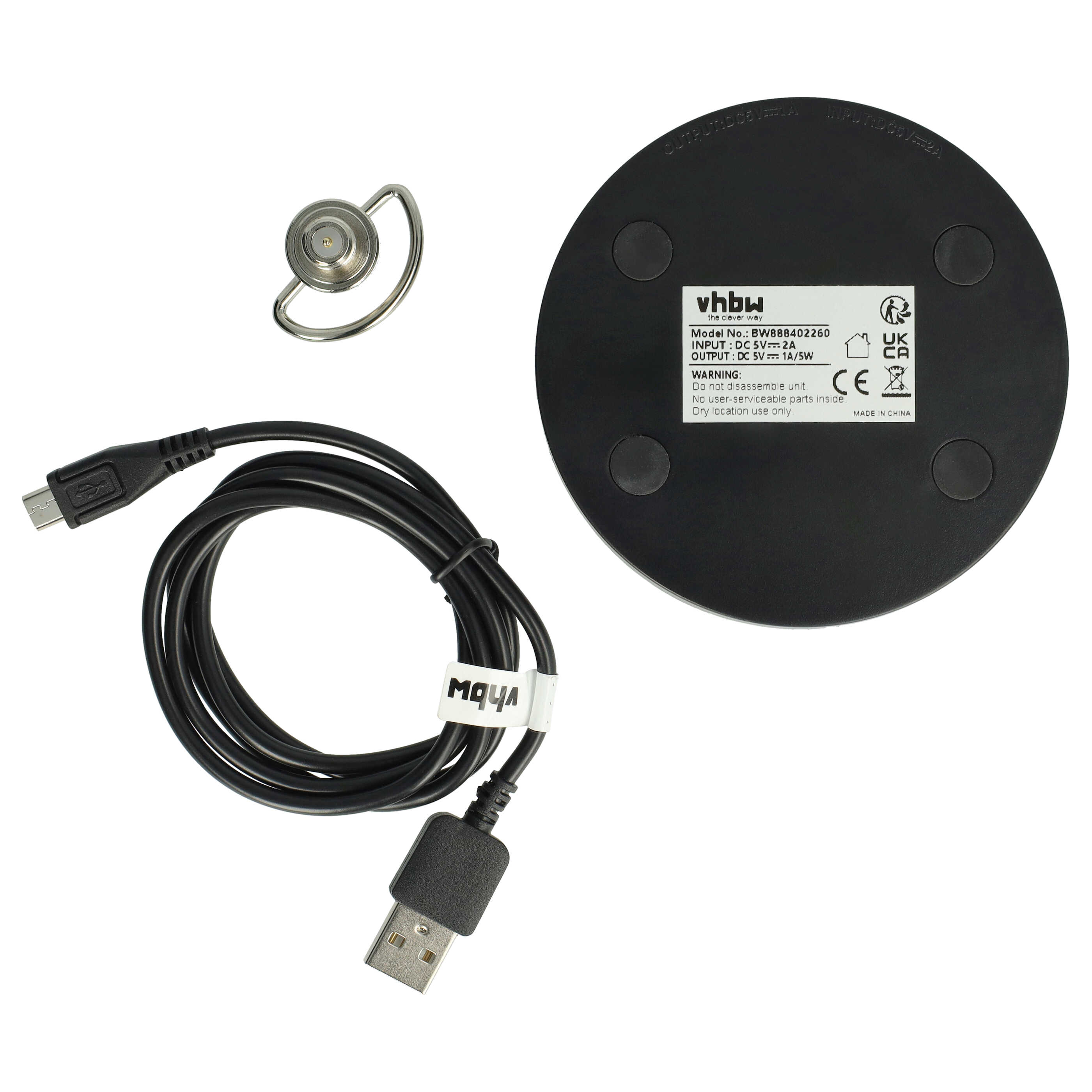 Ein schwarzes USB-Kabel mit einem Micro-USB-Stecker und ein Ring-Ohrhörer liegen neben einer runden schwarzen Basis.