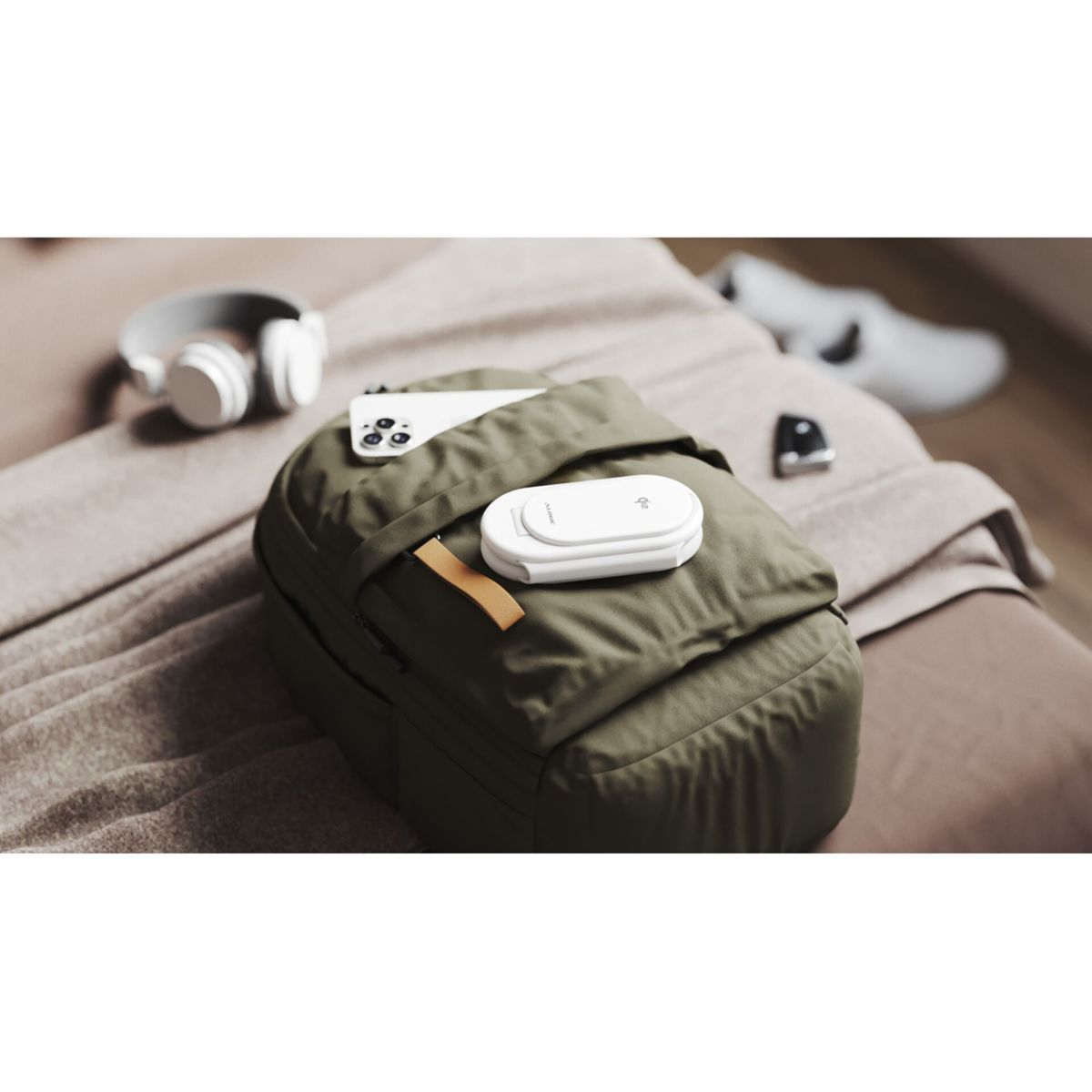 Ein grüner Rucksack mit weißem Ladegerät und Handy liegt auf einem Bett.