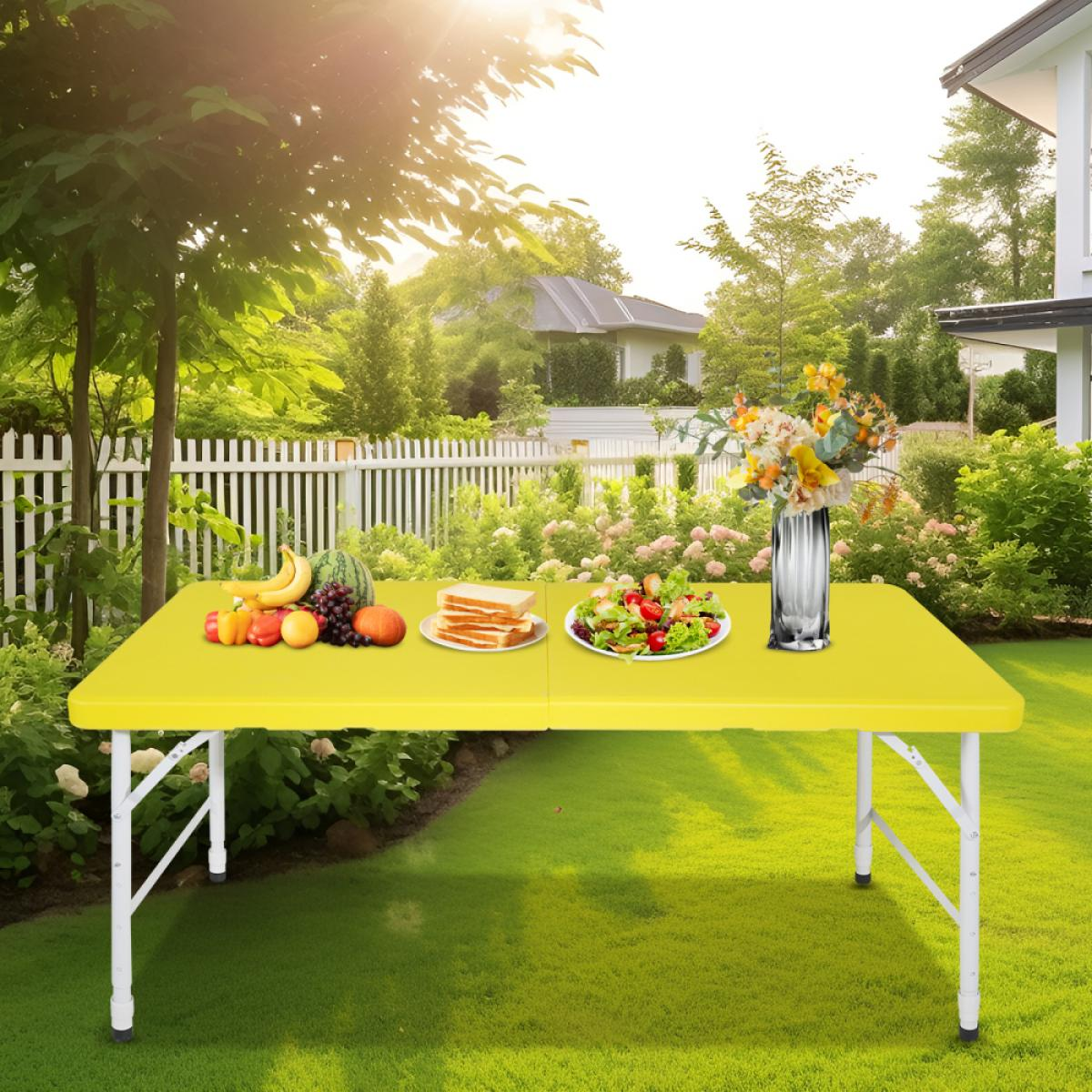 Gelber Tisch mit Obst, Sandwiches und Salat im Garten.