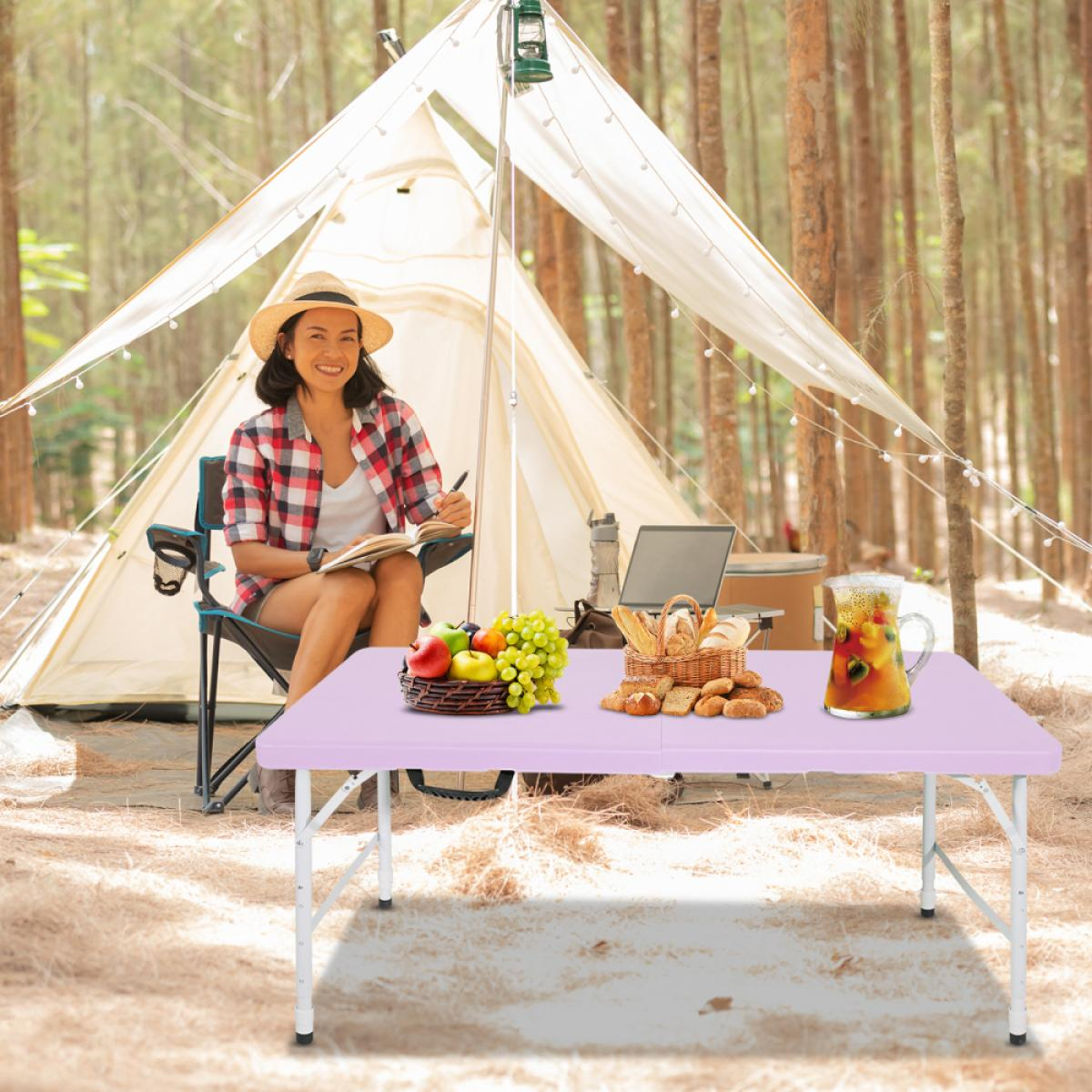Frau im karierten Hemd sitzt beim Camping und schreibt. Obst, Brot und Saft stehen auf dem Tisch.