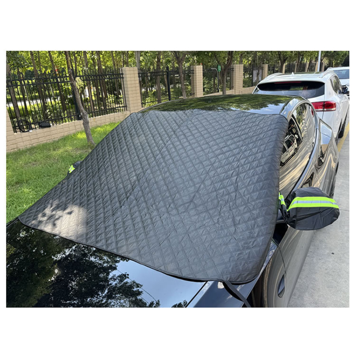Schwarze, gesteppte Autoabdeckung über der Windschutzscheibe, daneben ein weißes Auto.